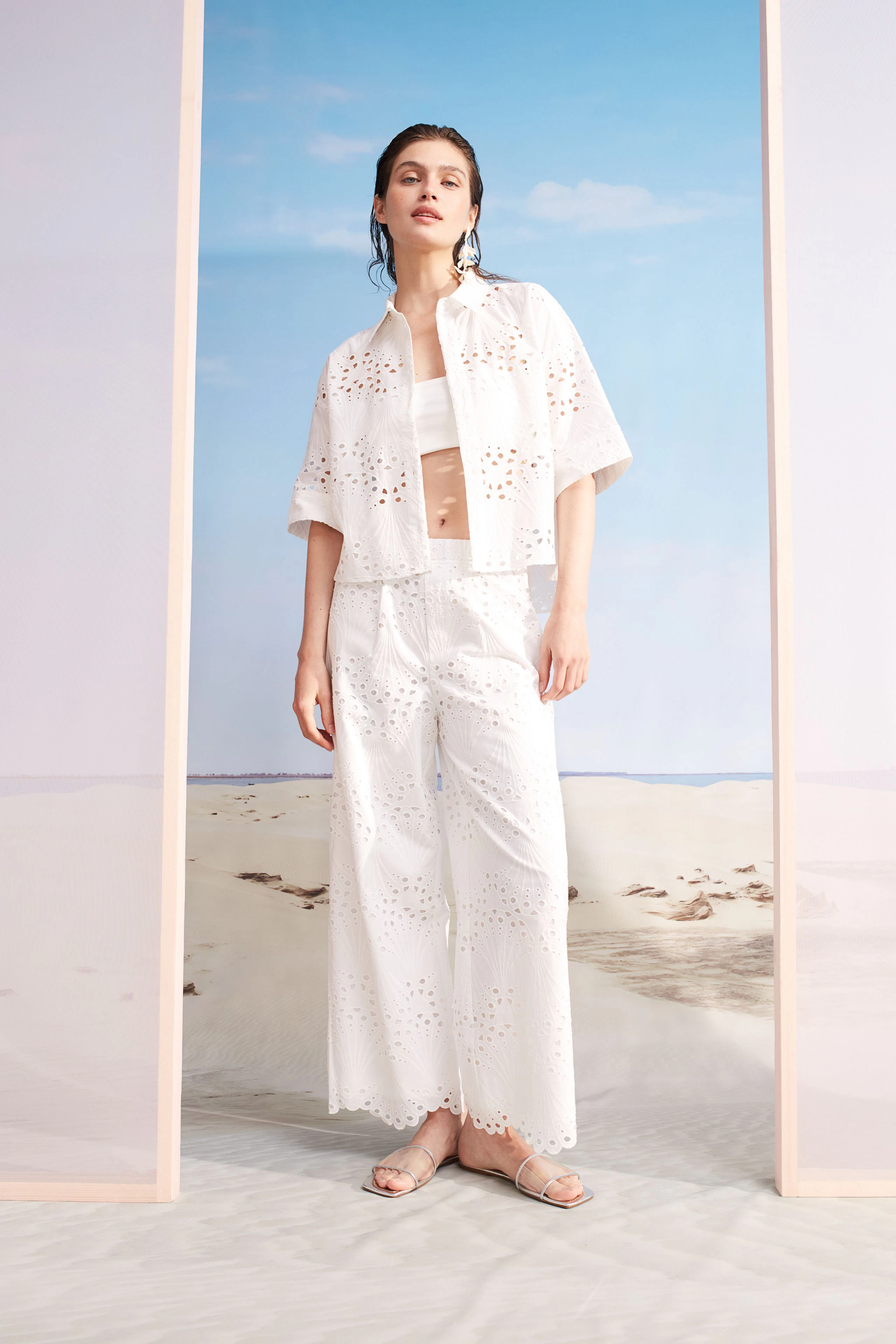 Moderne Damen-Culotte: Frau in weißer, luftiger Culotte mit Lochmuster und passendem Oberteil.