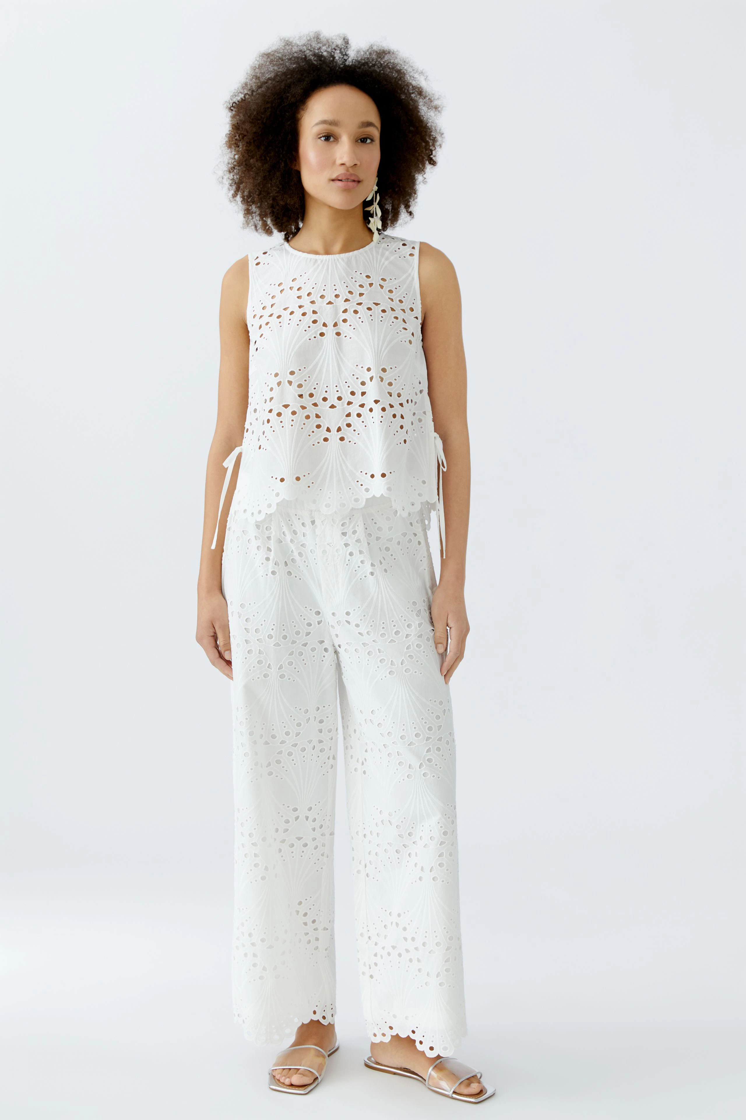 Luftige Damen-Culotte: Frau in weißer, durchbrochener Culotte mit passendem Top steht entspannt.
