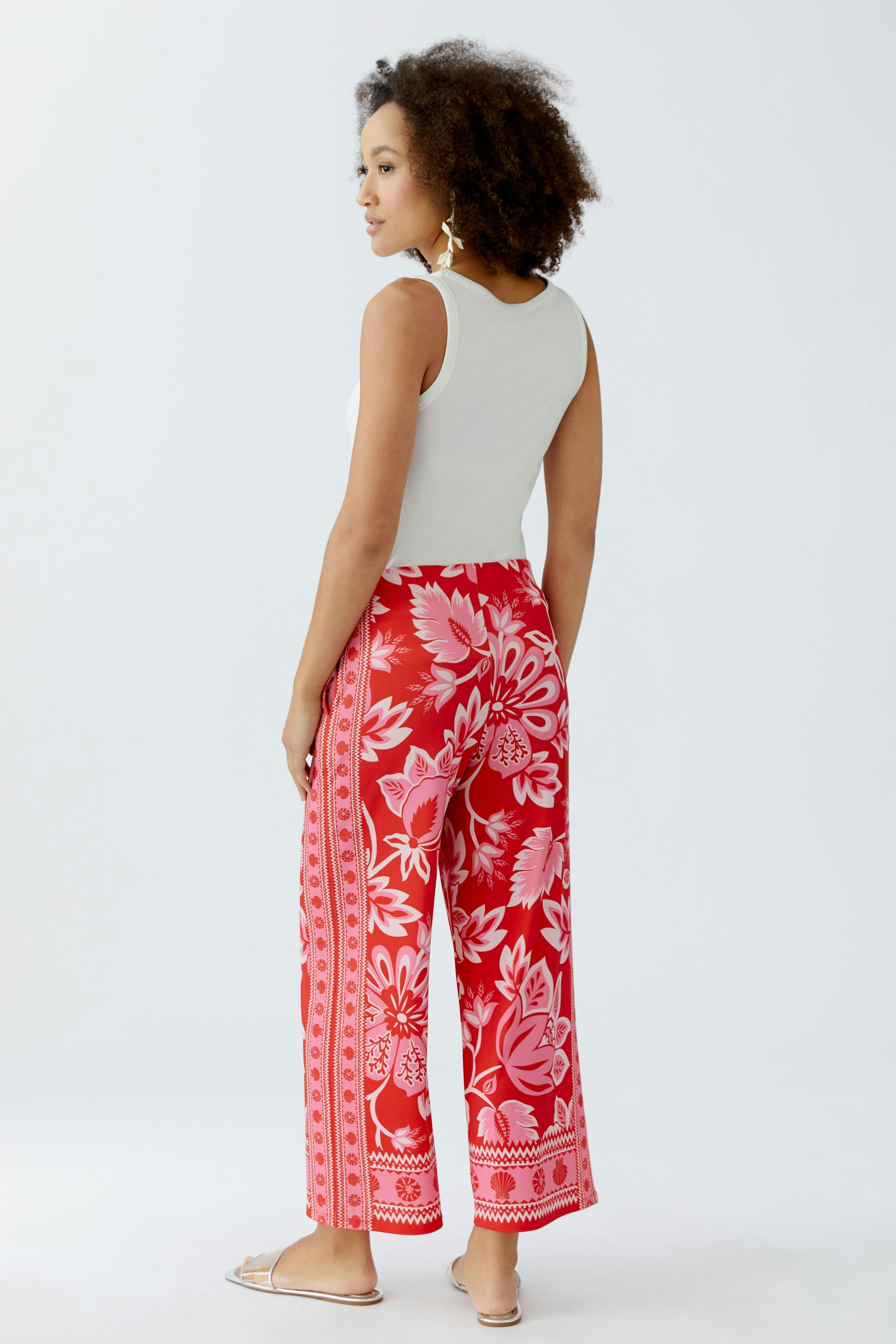 Casual women's pants: A woman in vibrant red floral wide-leg pants, showcasing a relaxed fit.