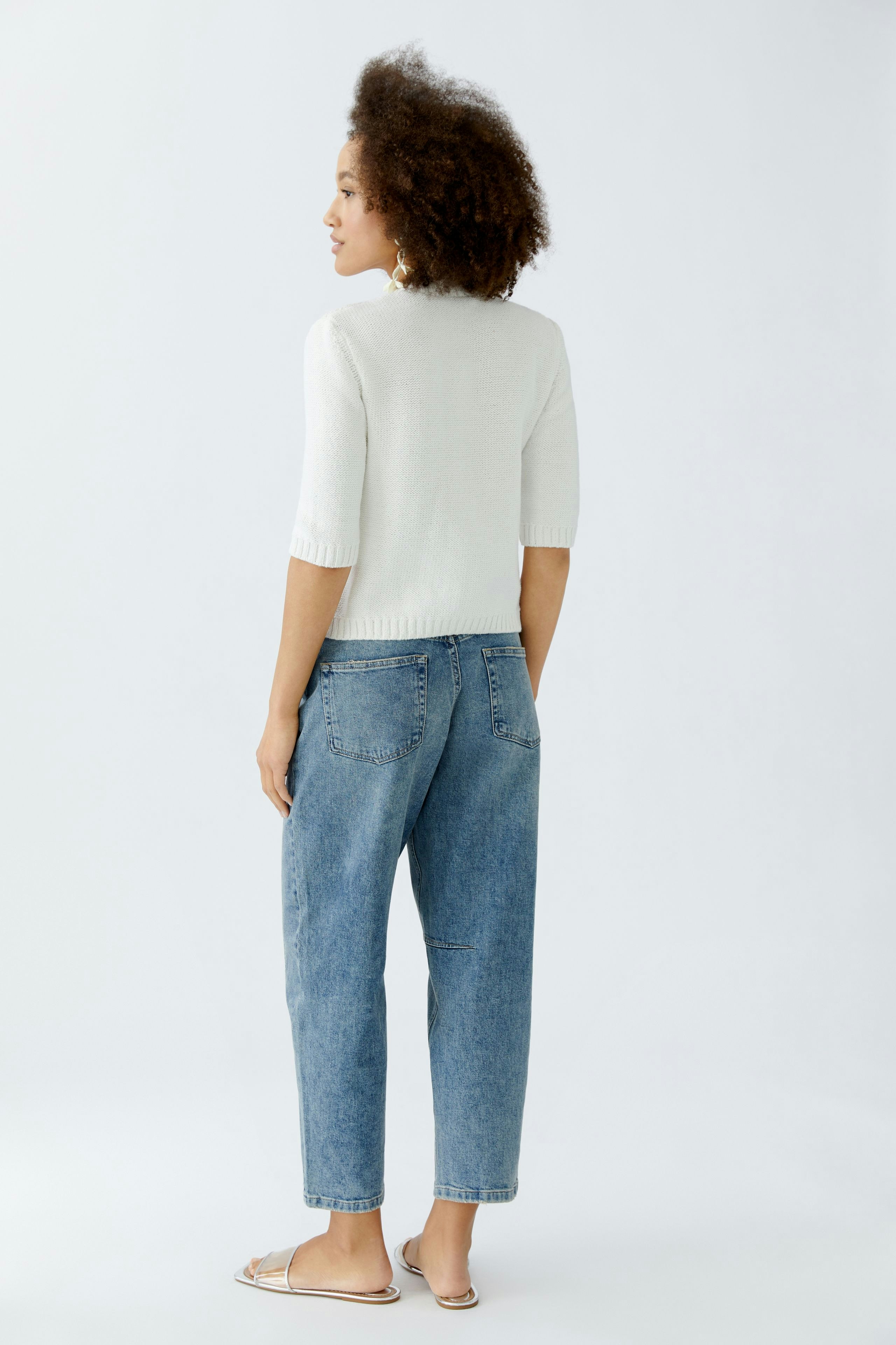 Casual women's cardigan: A woman in a light cardigan with short sleeves and relaxed jeans.