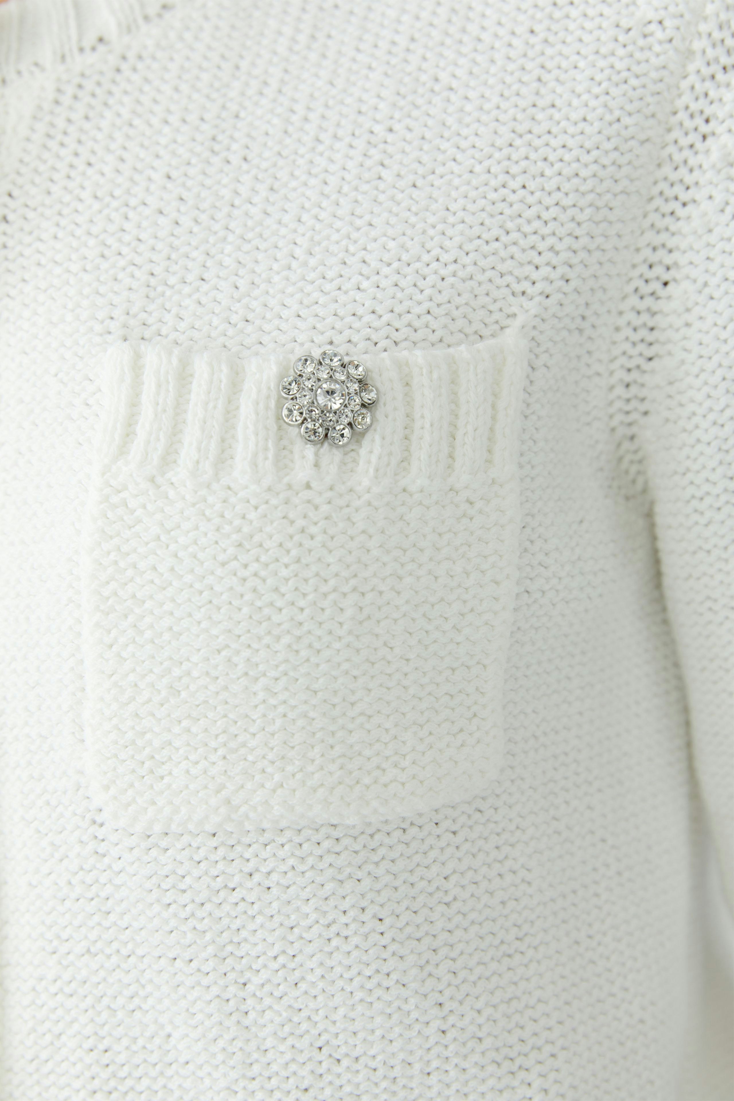 Casual women's cardigan: Close-up of a white knitted cardigan with a decorative pocket.