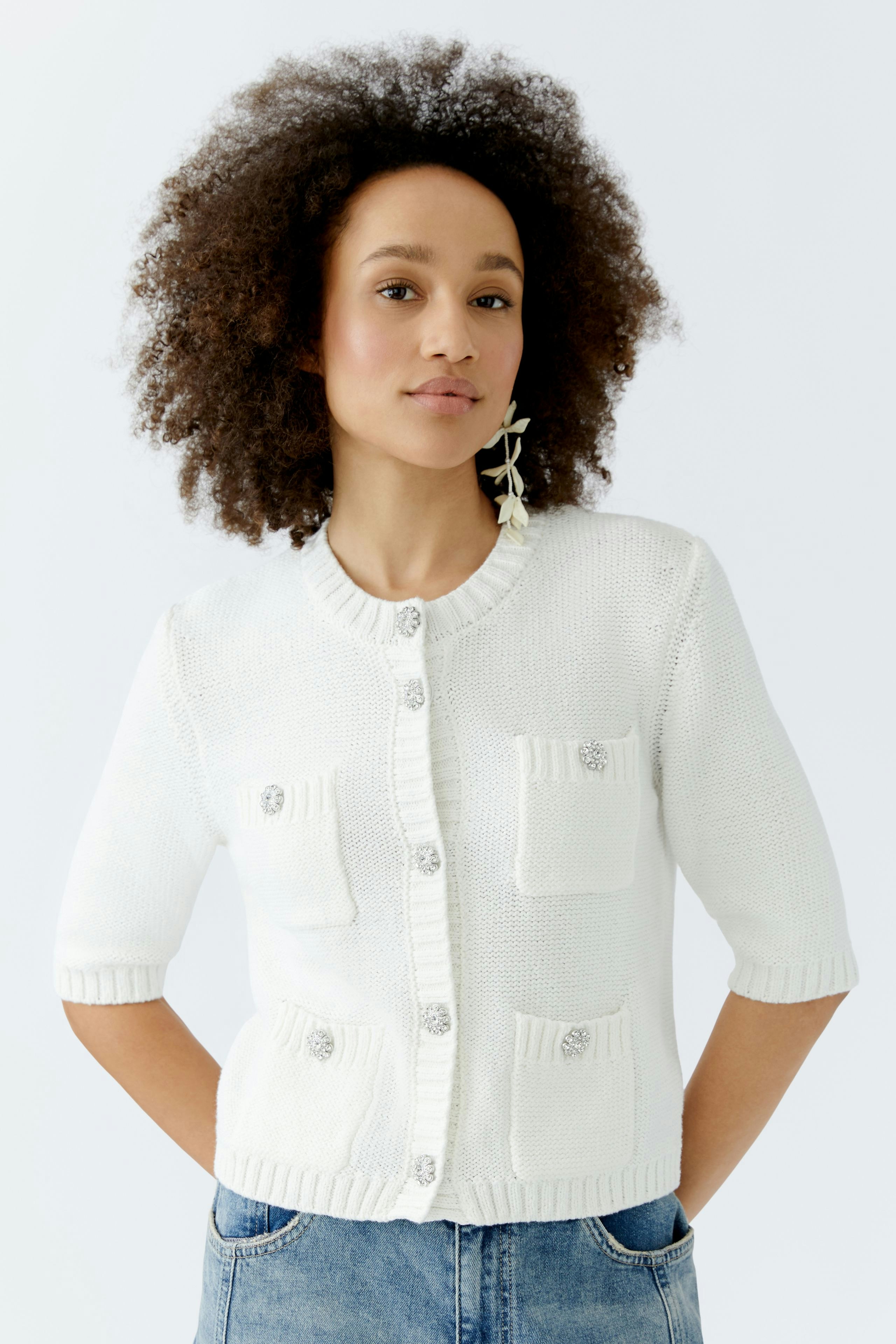 Casual women's cardigan: A woman in a white cardigan with pockets and short sleeves, styled with denim.