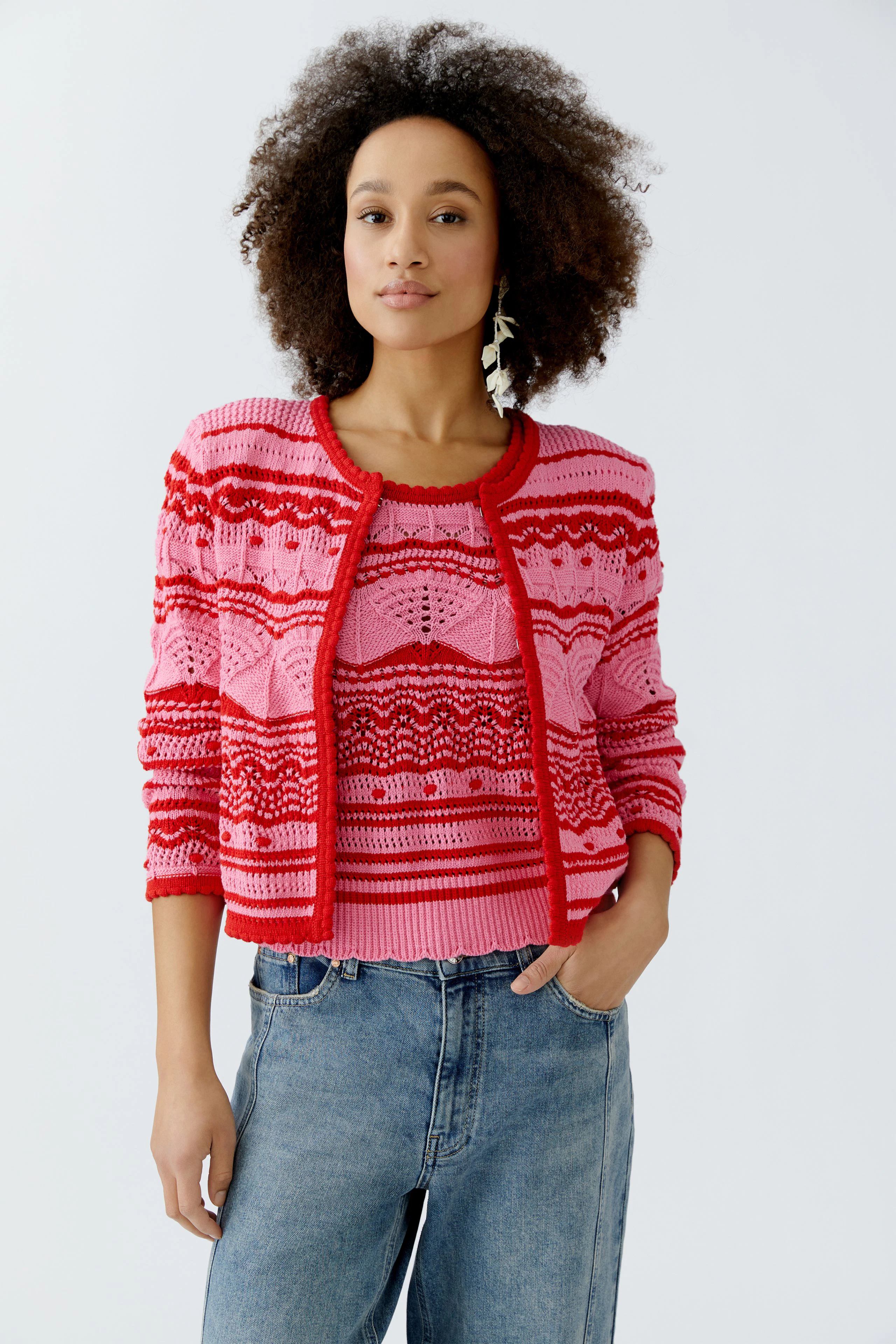 Bunte Damen-Strickjacke: Frau mit lockigem Haar trägt eine rot-pink gestreifte Strickjacke.