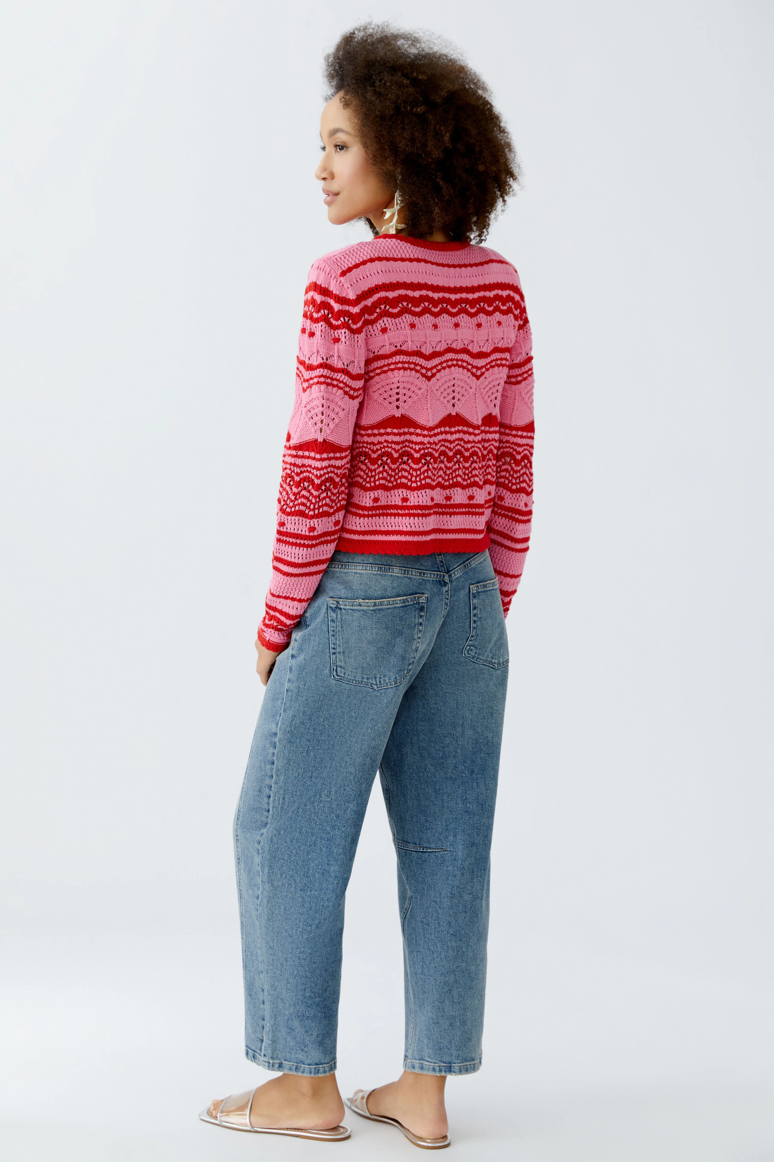 Bunte Damen-Strickjacke: Frau mit lockigem Haar trägt eine pink-rot gestreifte Strickjacke.