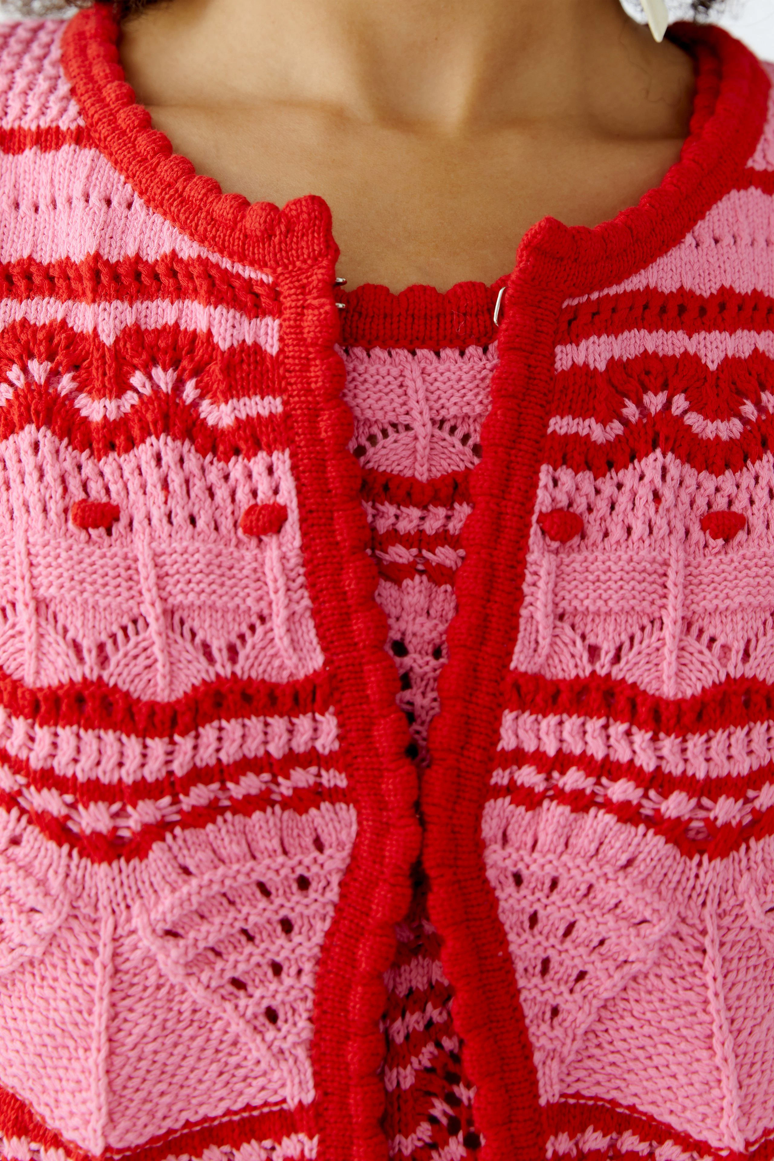 Bunte Damen-Strickjacke in Pink und Rot mit auffälligem Muster und Knöpfen.
