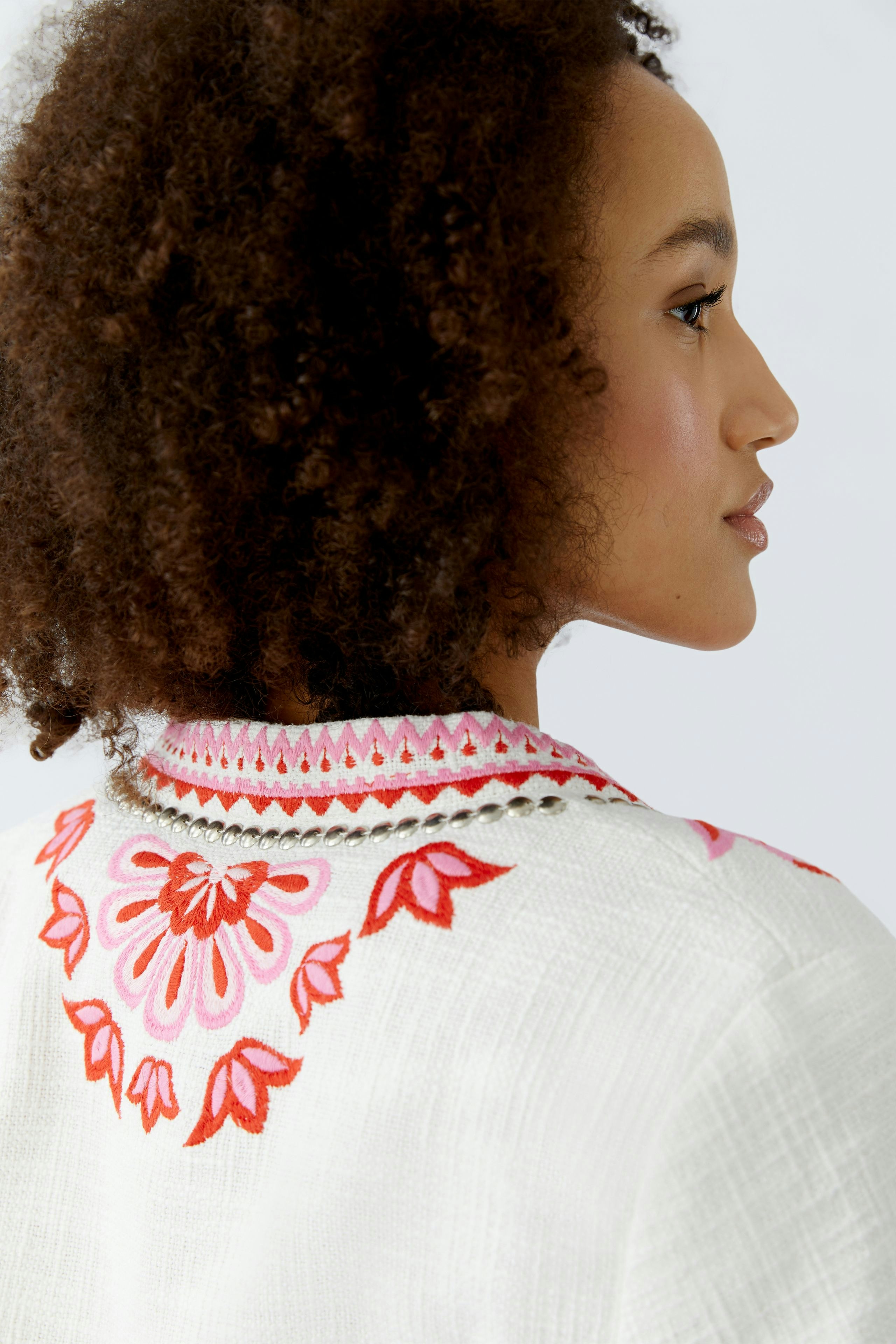 Stylish women's jacket with colorful embroidery, showcasing a woman with curly hair.