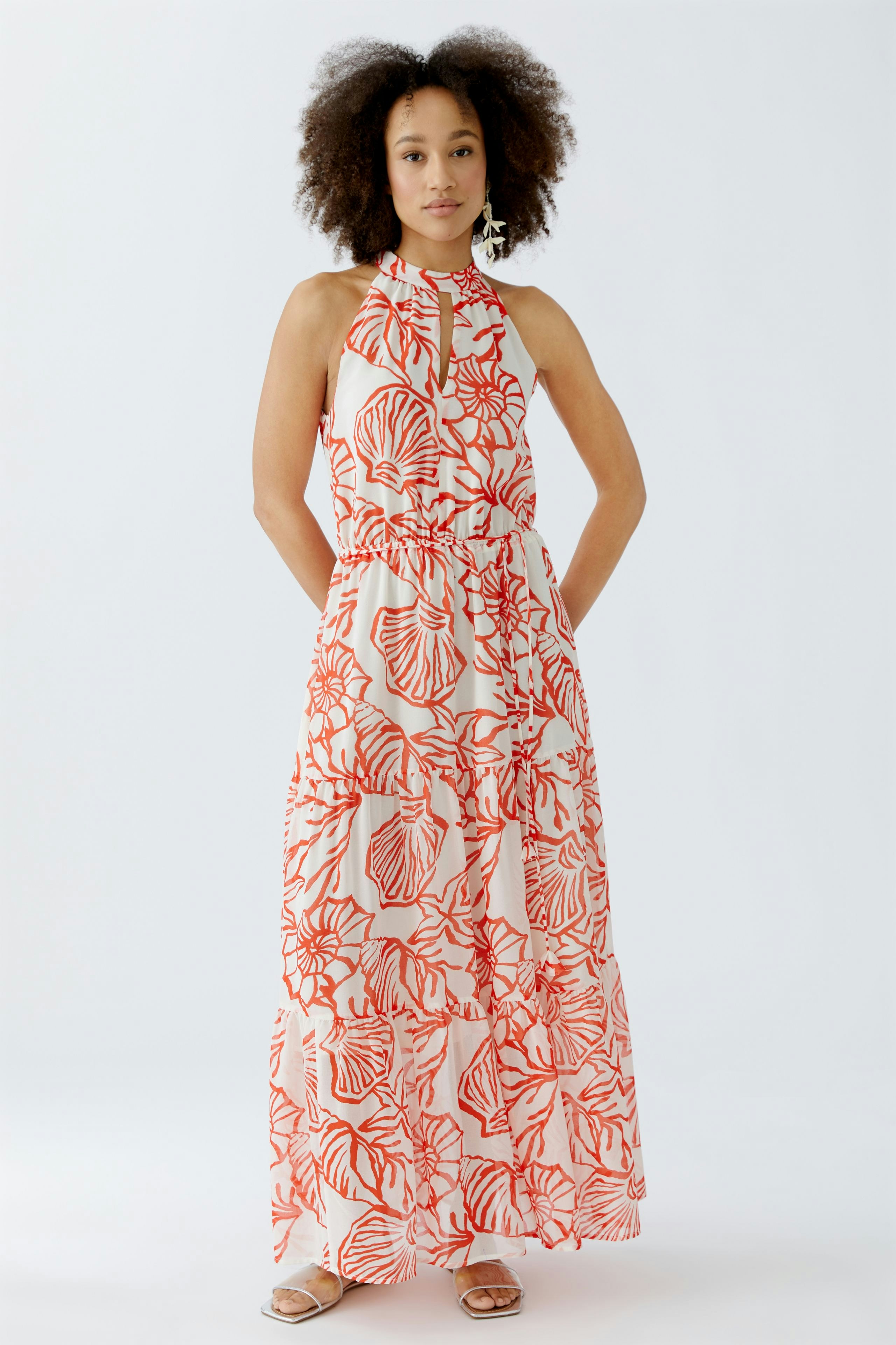 Maxikleid: Frau in einem blumigen, langen Kleid mit halbem Kragen und lockerer Passform.