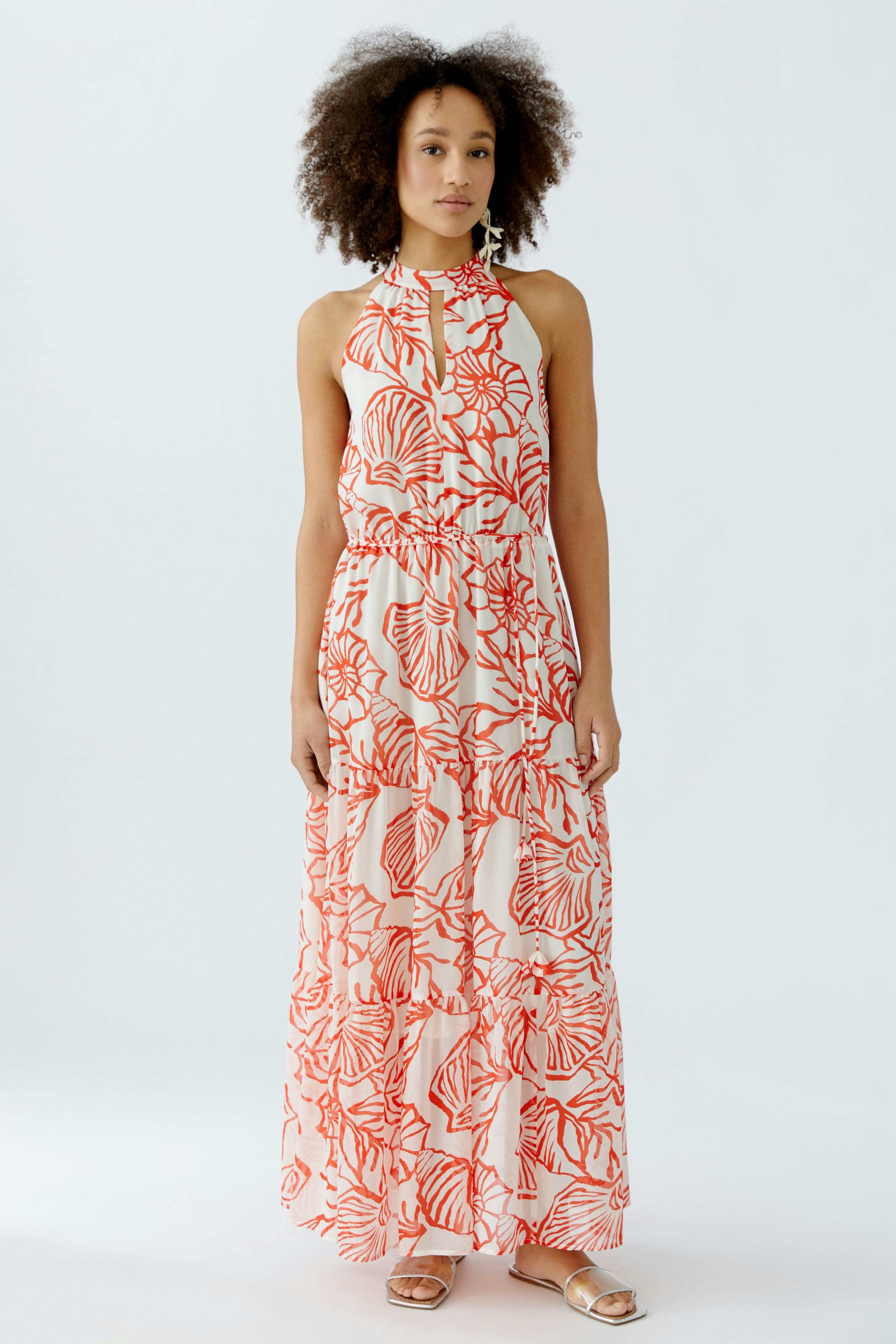 Maxikleid: Junge Frau in einem langen, blumigen Kleid mit rotem Muster und lockeren Stufen.