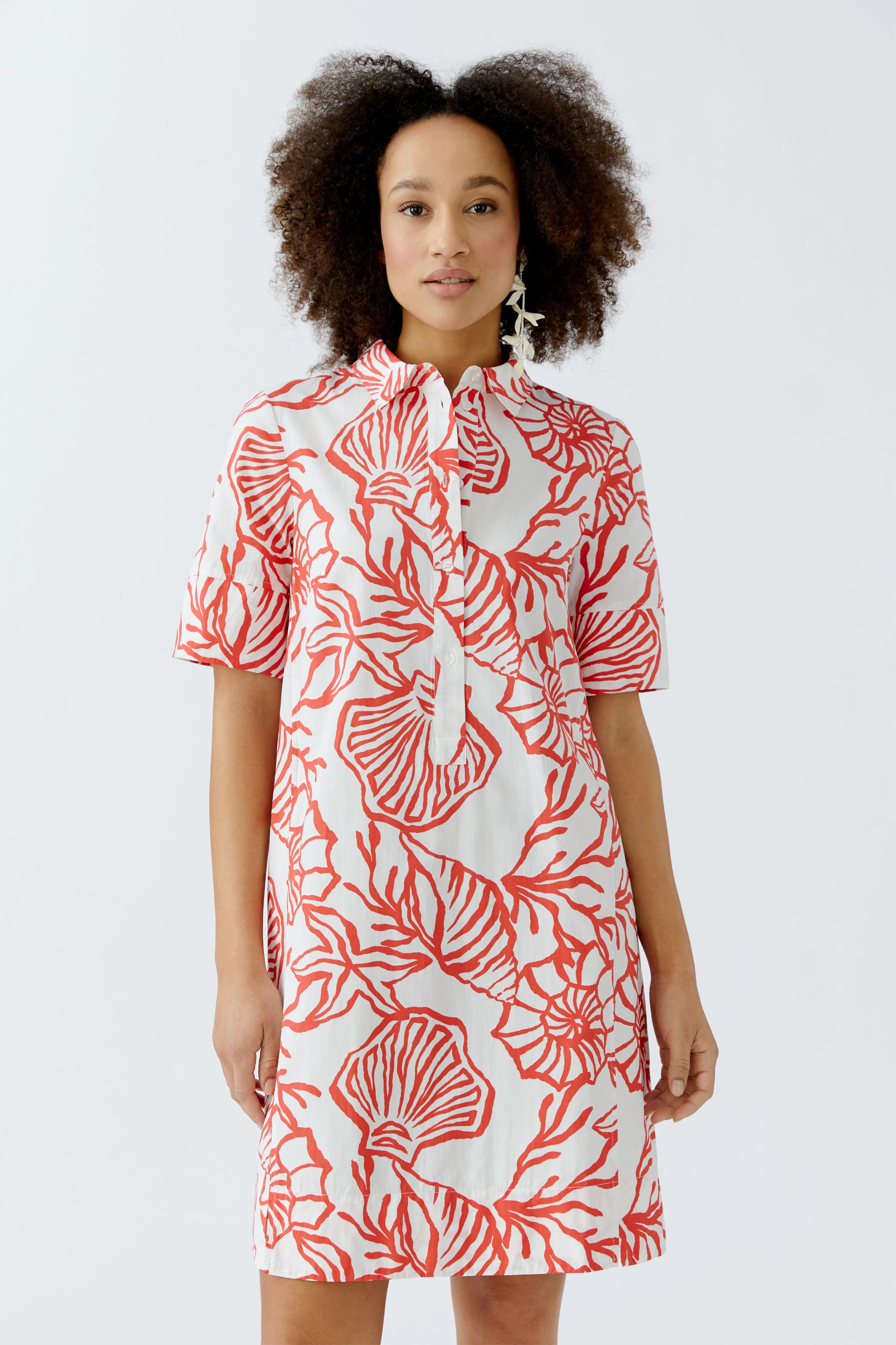 Hemdblusenkleid: Frau trägt ein kurzes, gemustertes Kleid mit kurzen Ärmeln und Stehkragen.