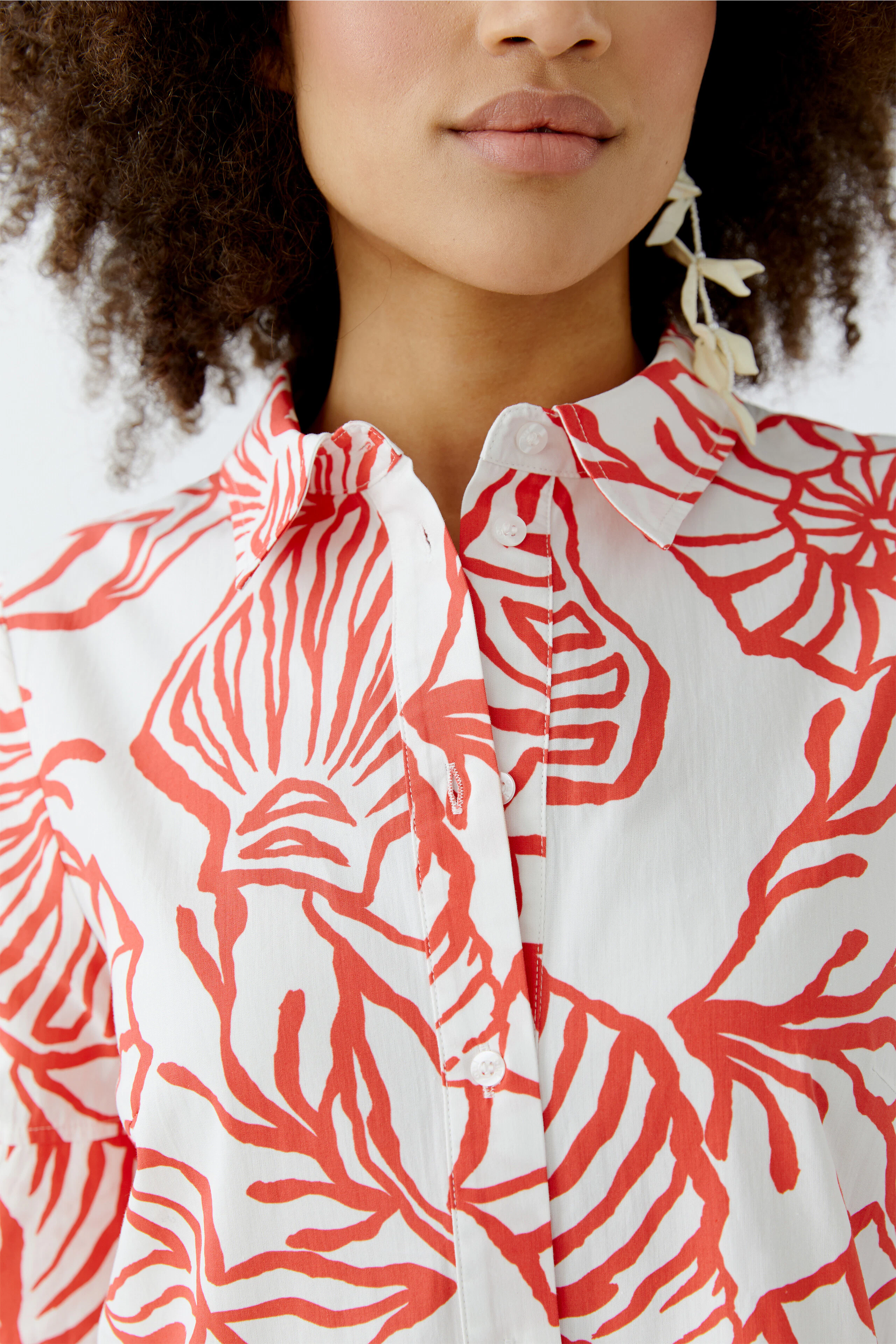 Hemdblusenkleid: Frau trägt ein weißes Kleid mit rotem Blattmuster und klassischem Kragen.