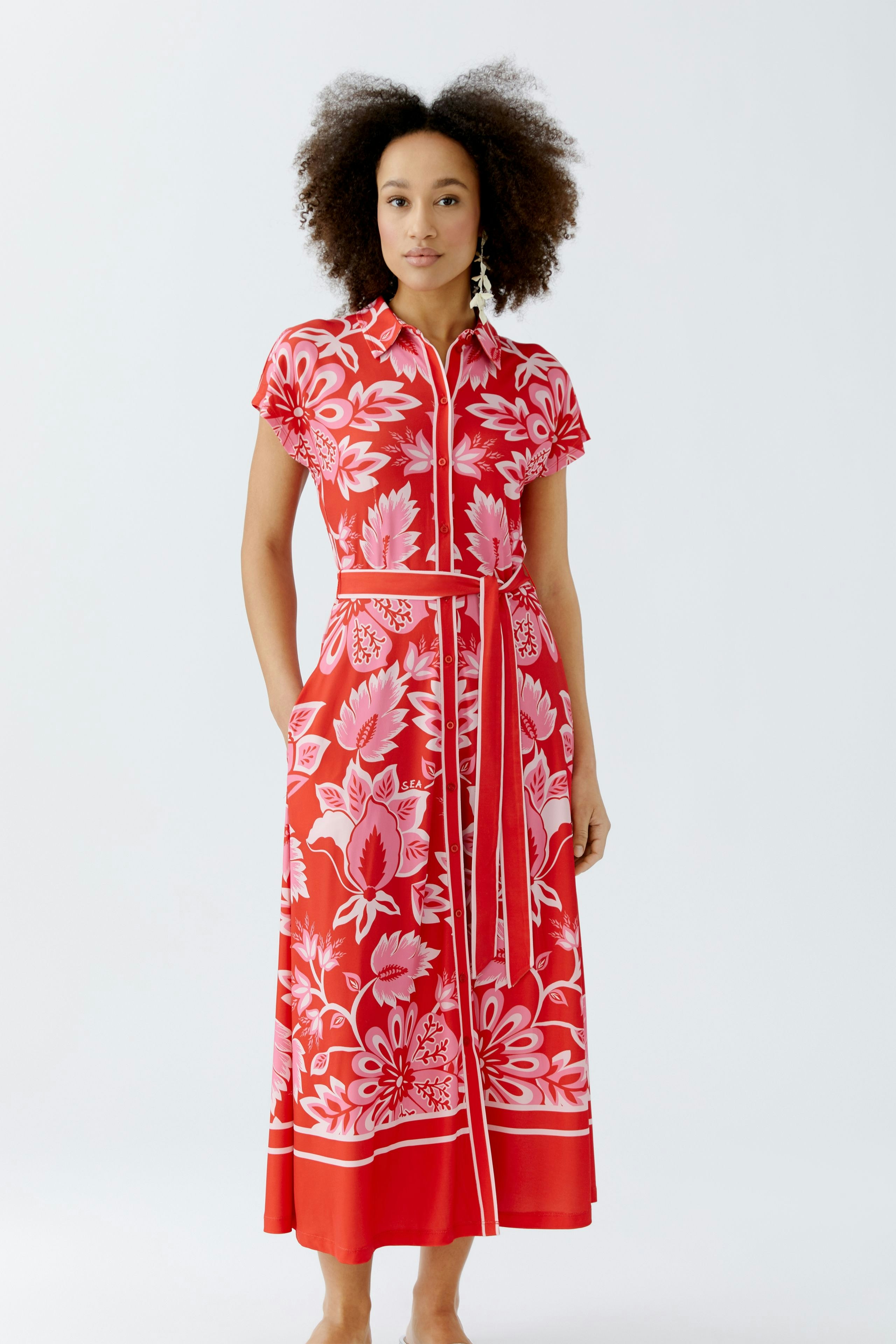 Shirt dress: A woman in a vibrant red shirt dress with floral patterns, featuring a belted waist.
