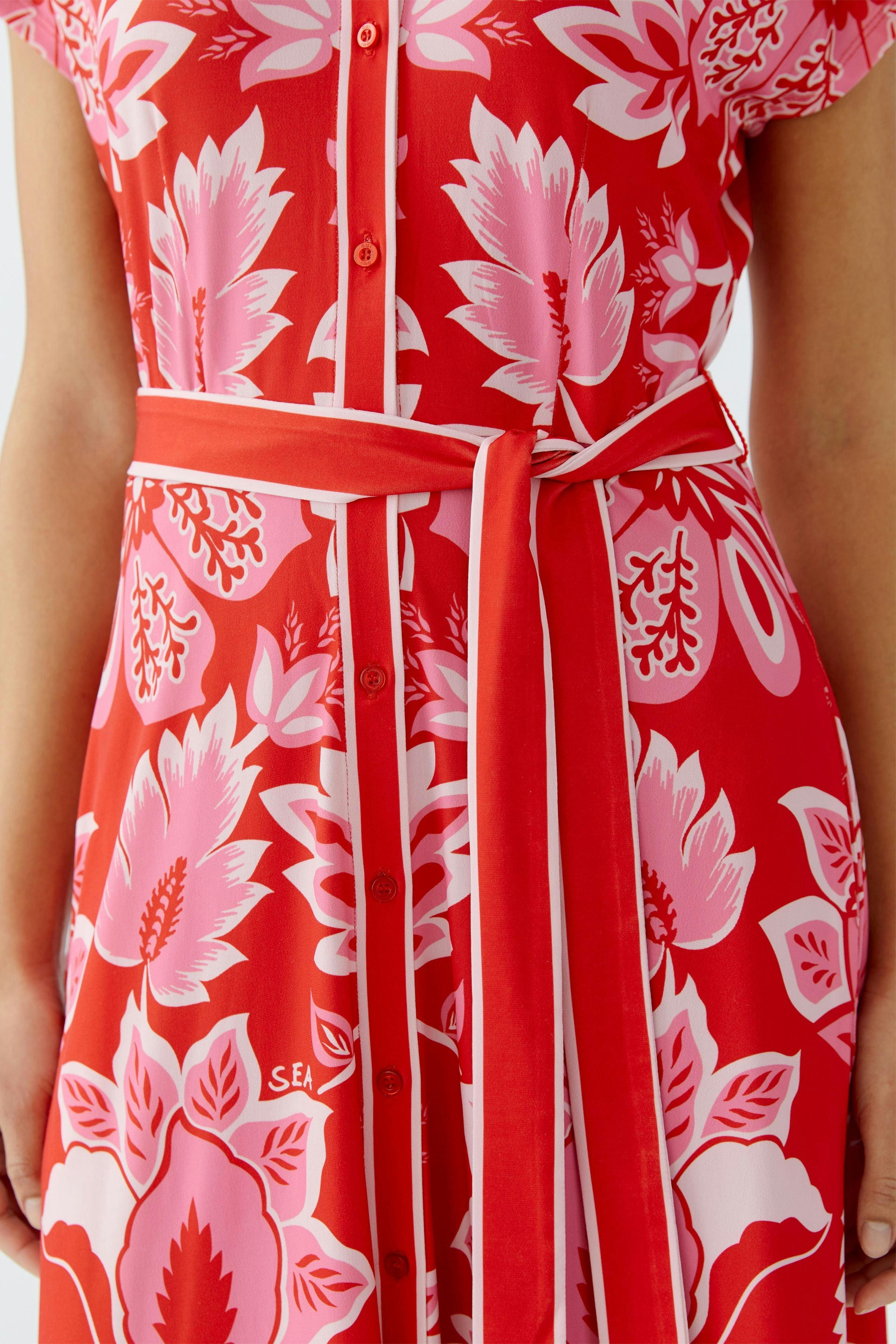 Colorful shirt dress: A woman in a vibrant red dress with floral patterns and a matching belt.