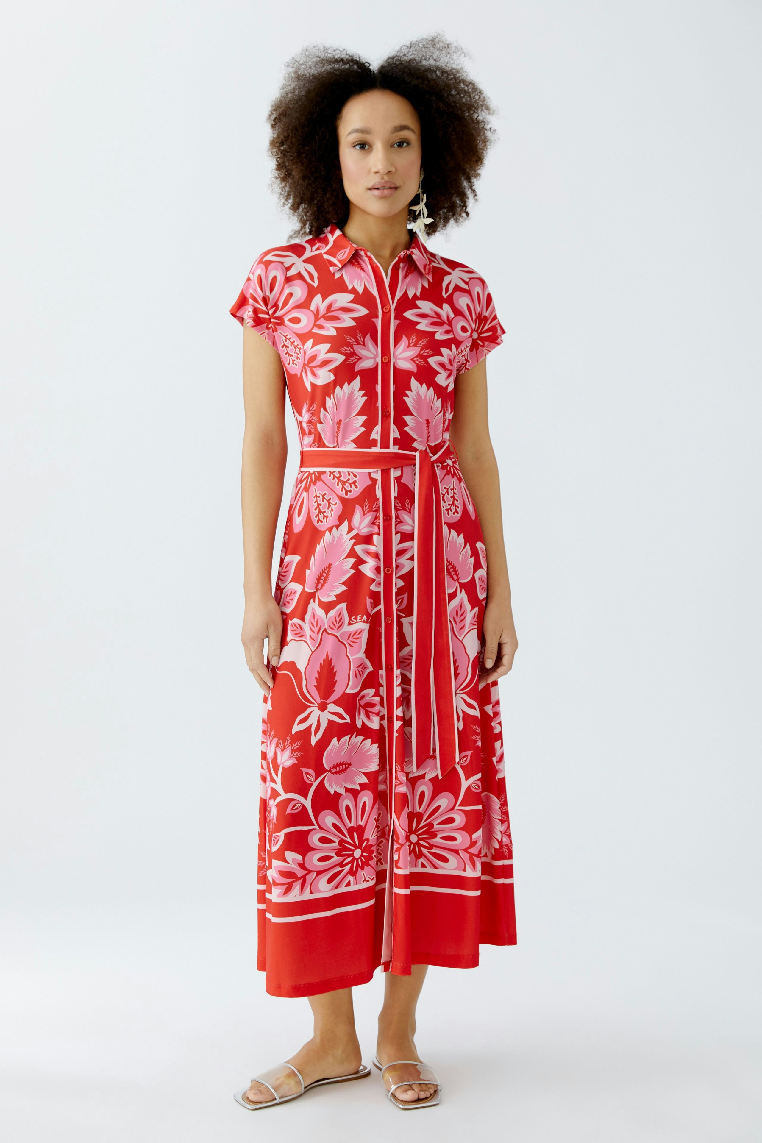 Floral shirt dress: Woman in a vibrant red dress with floral patterns and a belted waist.