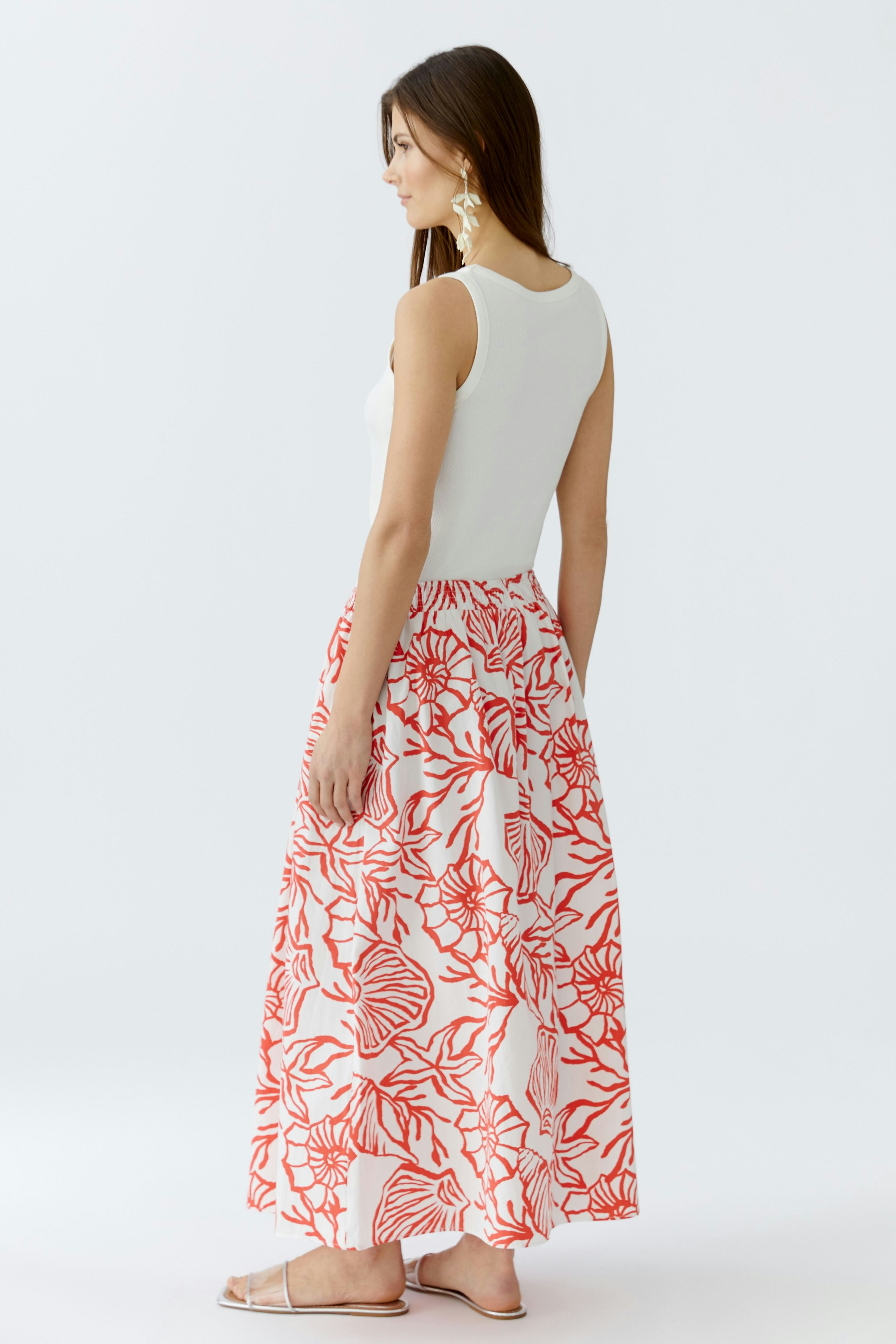 Casual maxi skirt: Woman in a white top and a flowy red floral maxi skirt, showcasing a relaxed style.