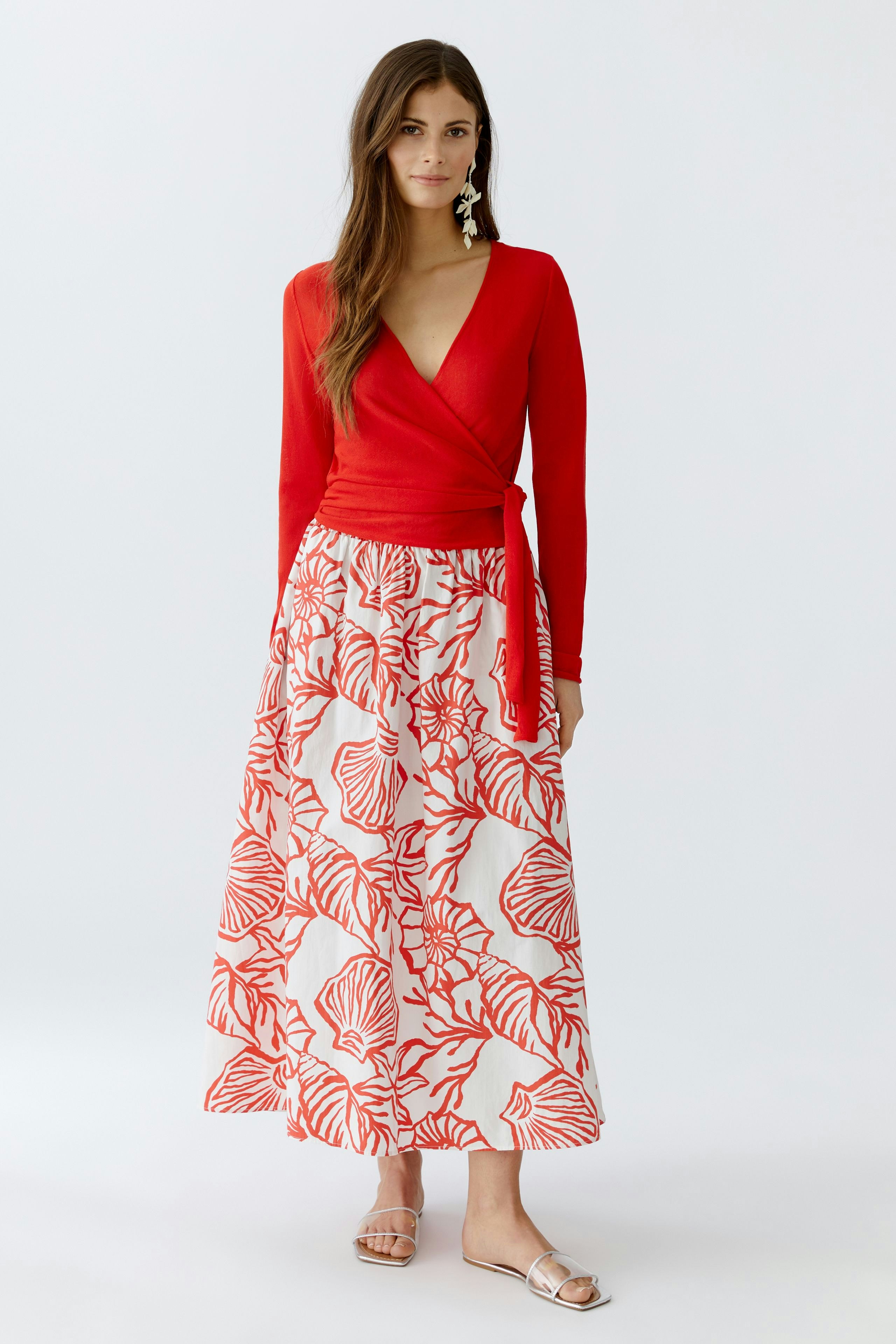 Casual maxi skirt: Woman in a red wrap top and a floral-patterned maxi skirt, standing confidently.