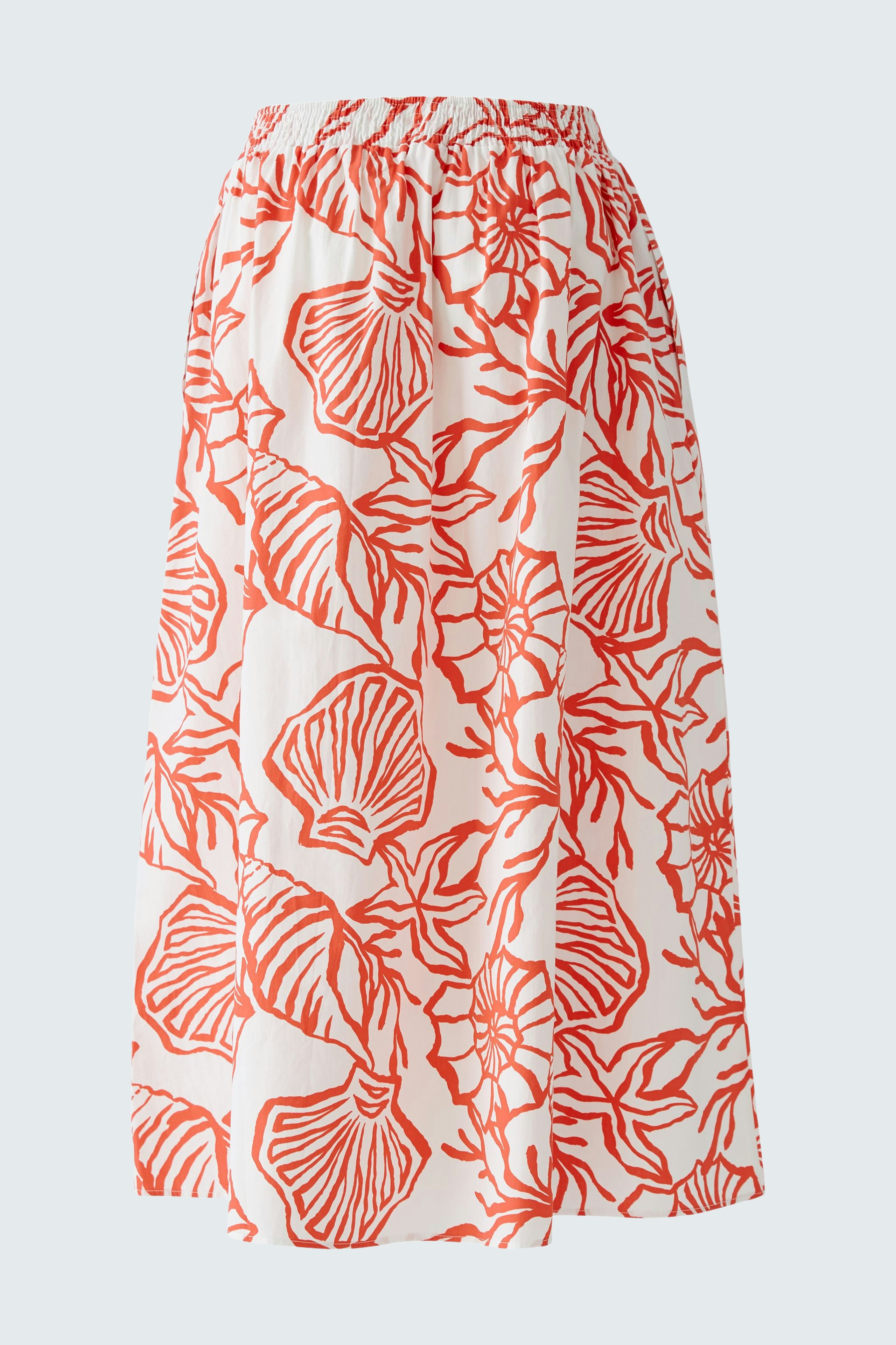 Casual maxi skirt: A woman in a white skirt with red floral patterns, featuring an elastic waistband.