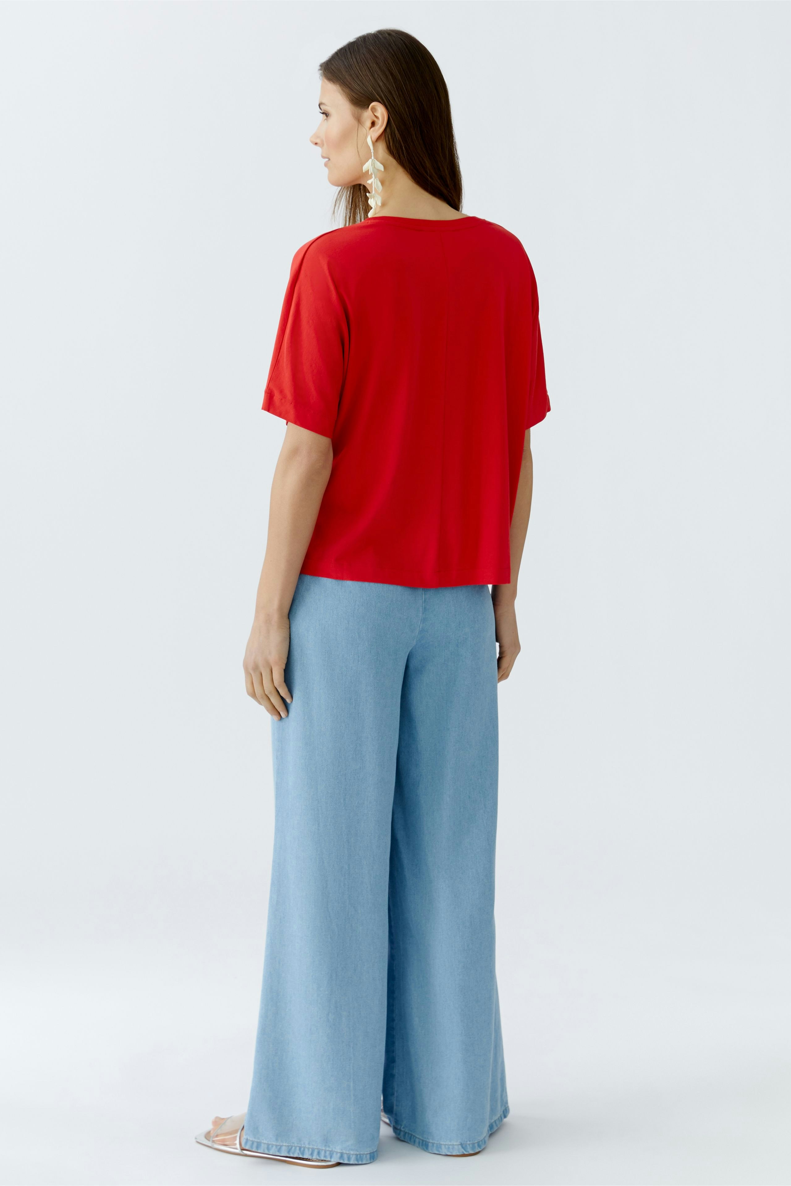 Casual women's T-shirt: A woman in a red T-shirt paired with light blue wide-leg jeans.