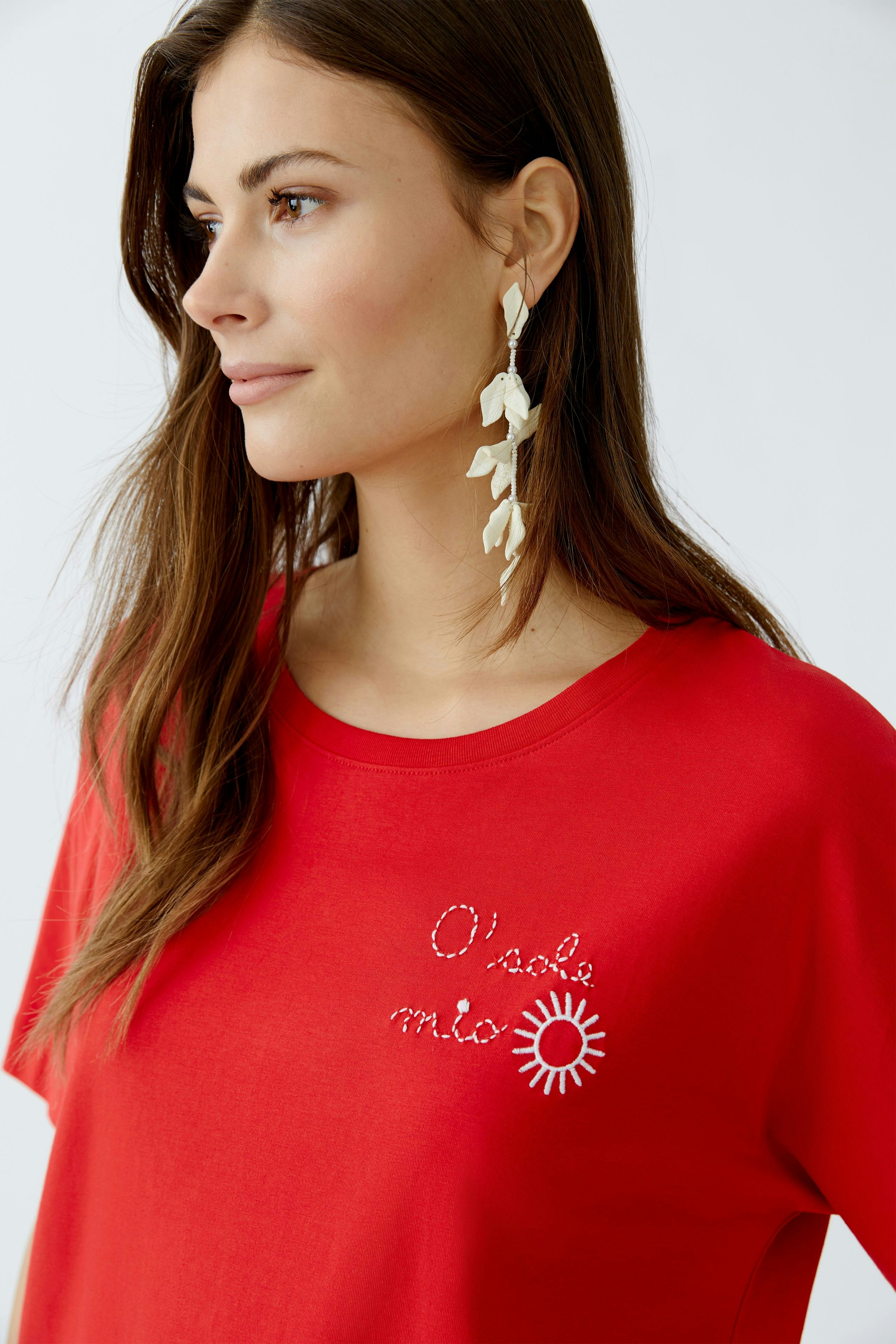 Casual women's T-shirt: Young woman in a red tee with sun graphic and sparkling text.