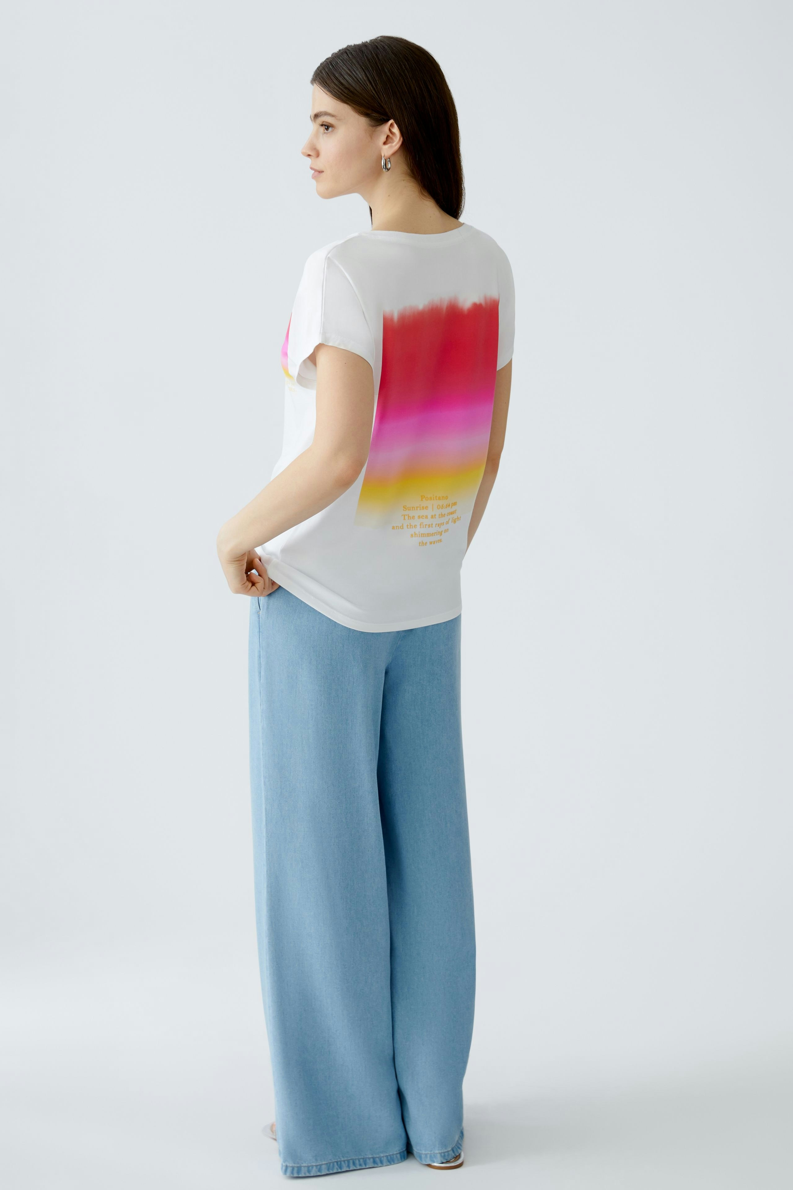 Casual women's T-shirt: Young woman in a white tee with a colorful gradient design and relaxed fit.
