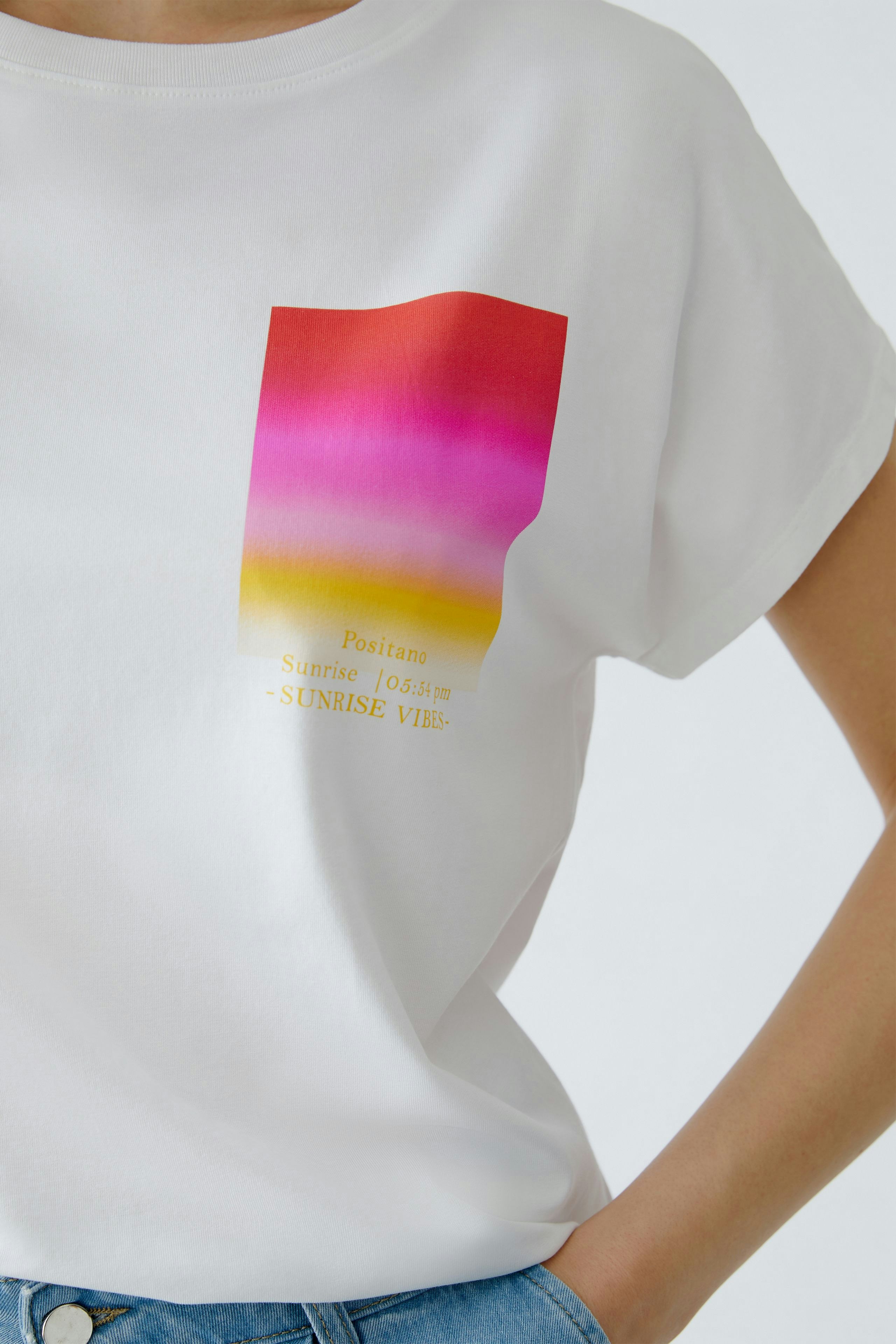 Casual women's T-shirt: A woman in a white tee featuring a colorful graphic design.