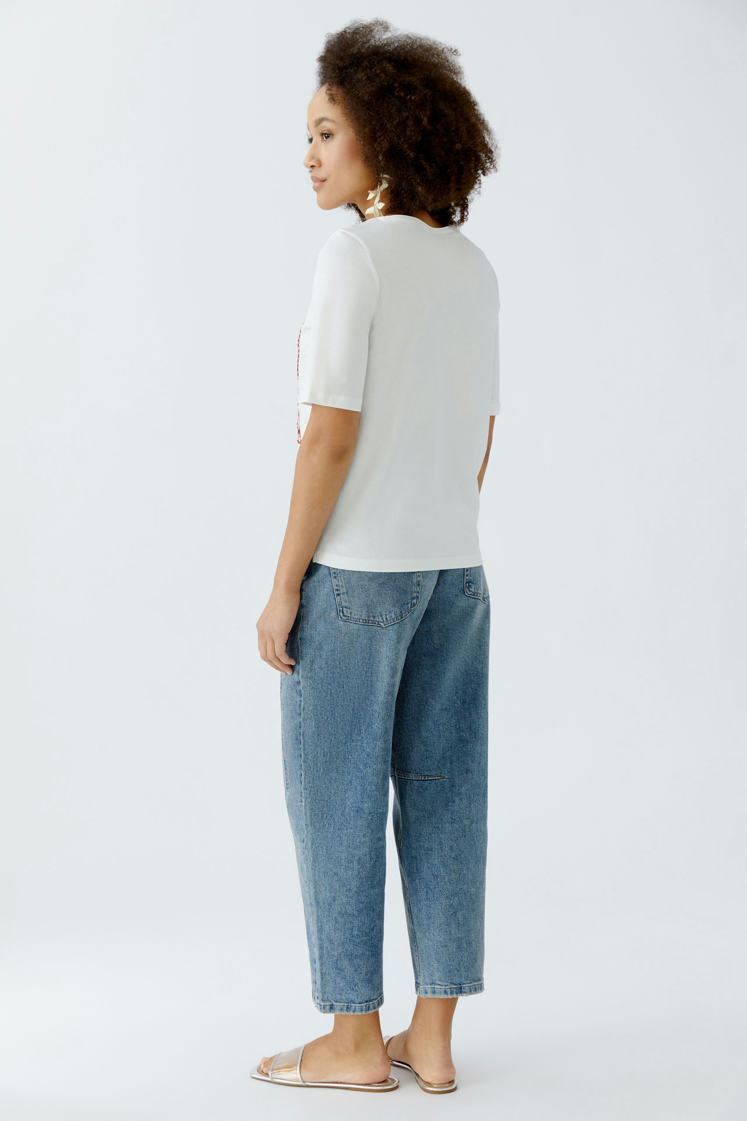 Damen-T-Shirt: Frau trägt ein weißes T-Shirt mit kurzen Ärmeln und lässigen Jeans.