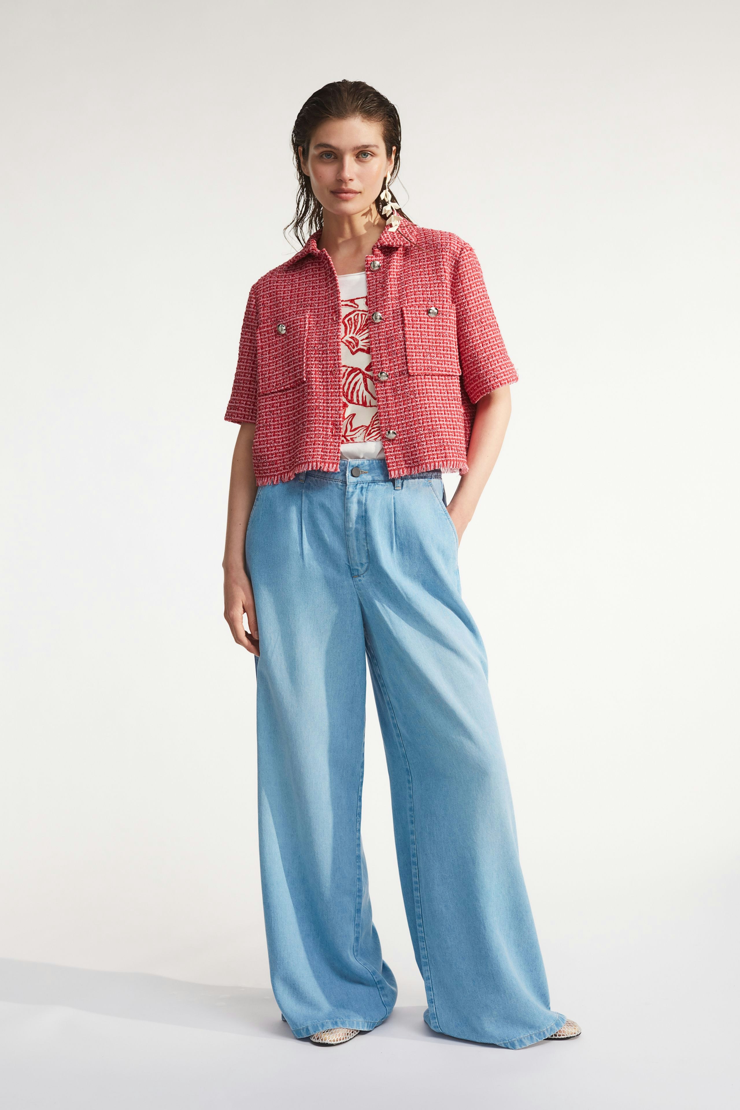 Damen-T-Shirt: Frau trägt ein buntes T-Shirt mit floralem Muster, kombiniert mit einer lässigen Jacke.