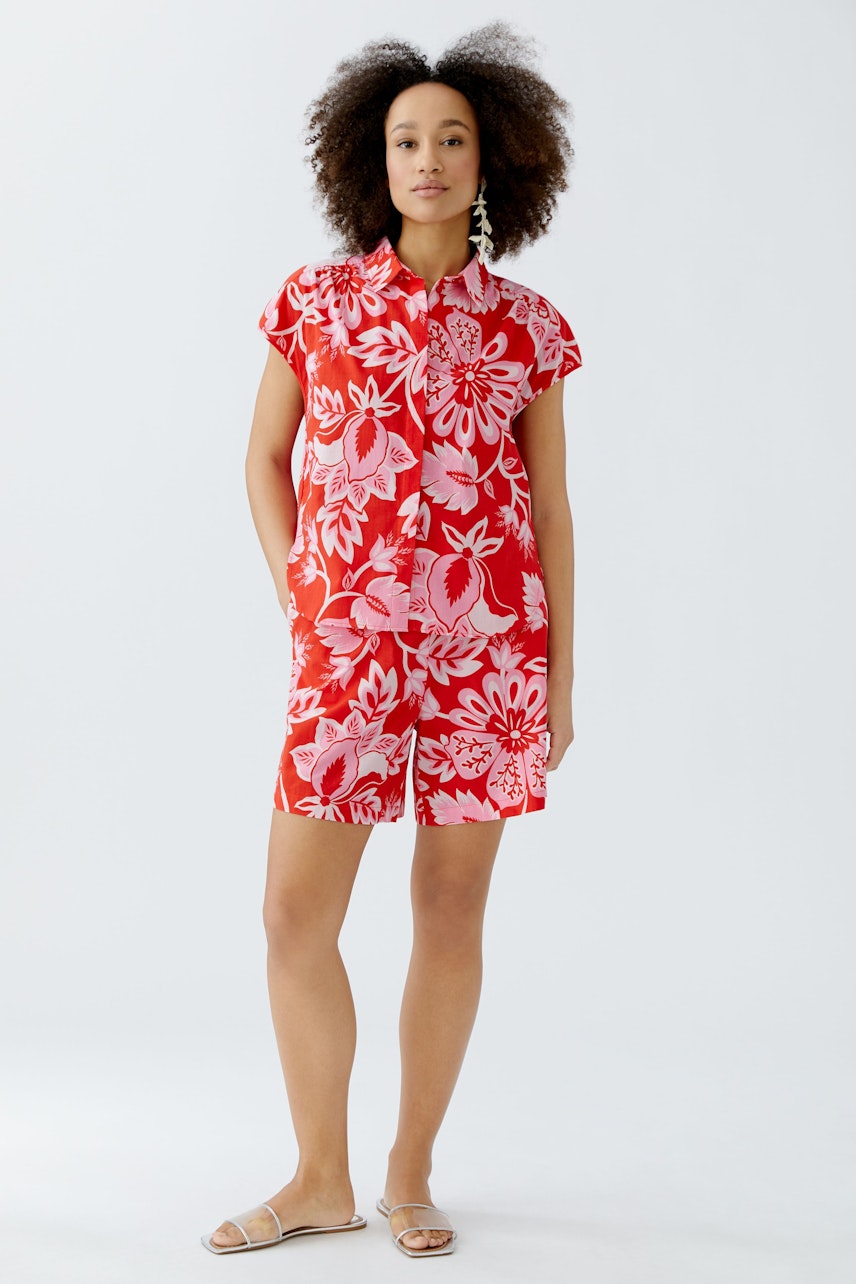 Bequeme Damen-Shorts: Frau in roten Shorts mit floralem Muster, ideal für warme Tage.
