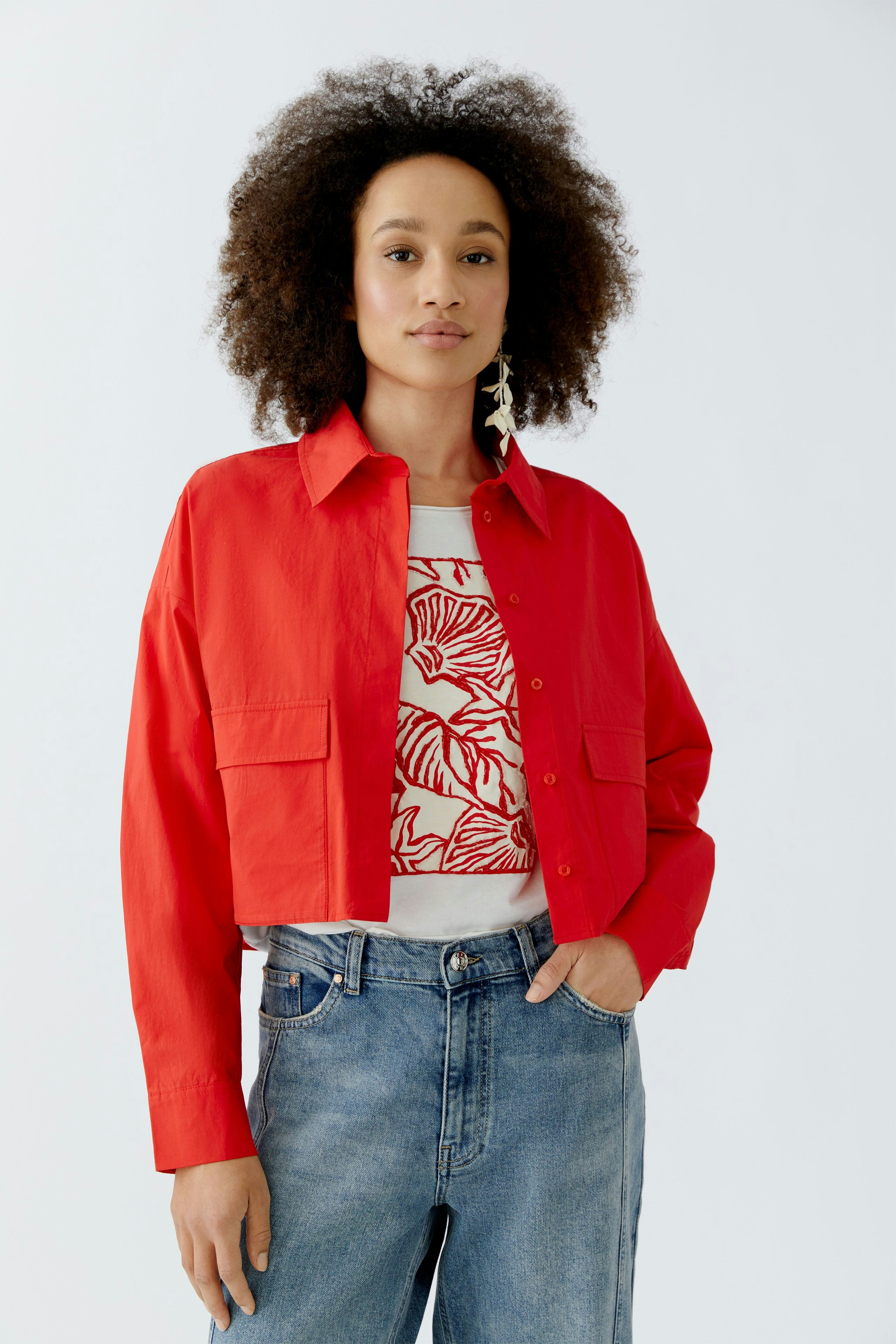 Rote Damen-Bluse: Frau trägt eine kurz geschnittene Bluse mit zwei Taschen und lässigem Design.