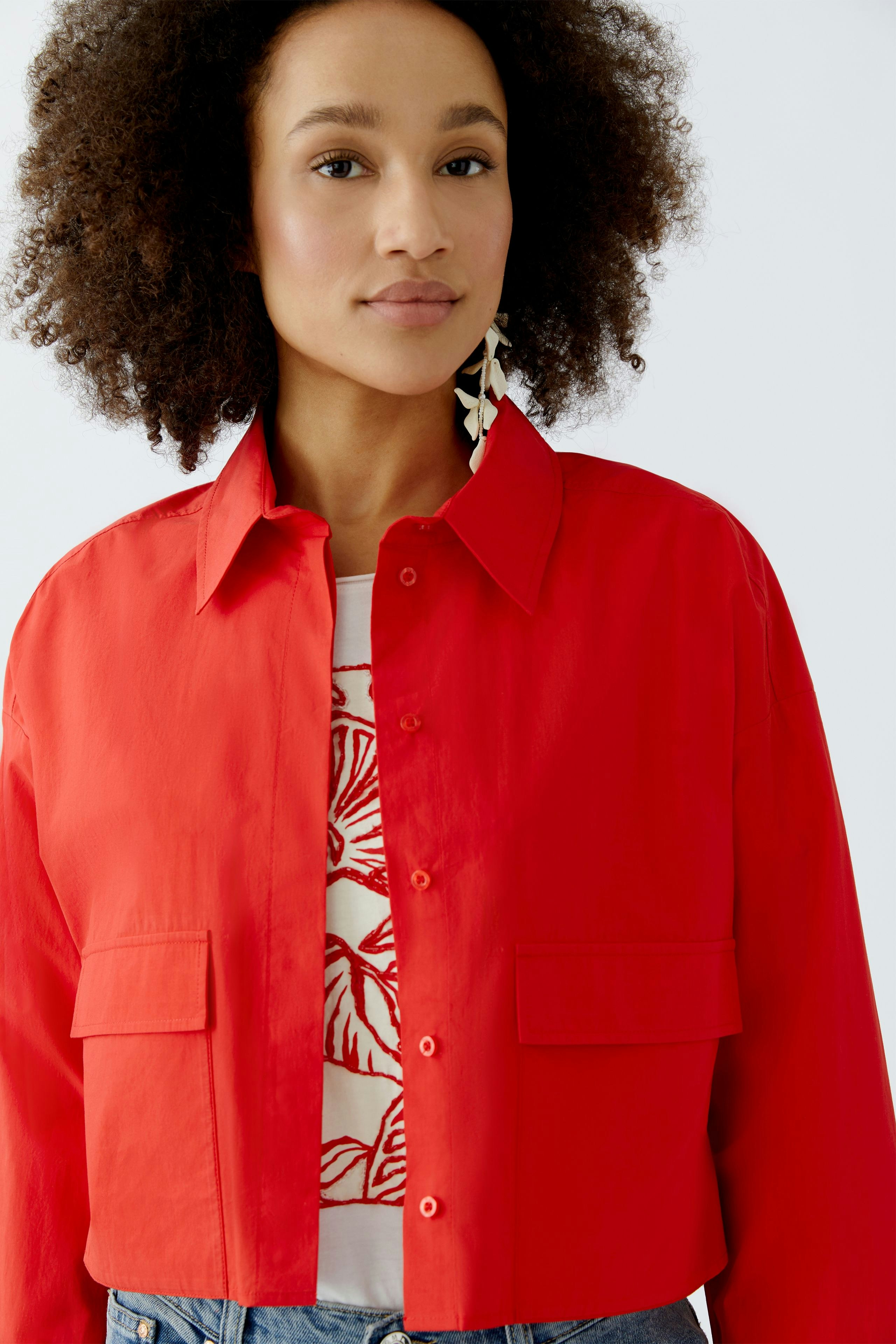 Moderne Damen-Bluse: Frau in roter Bluse mit zwei Taschen und lässigem Look.