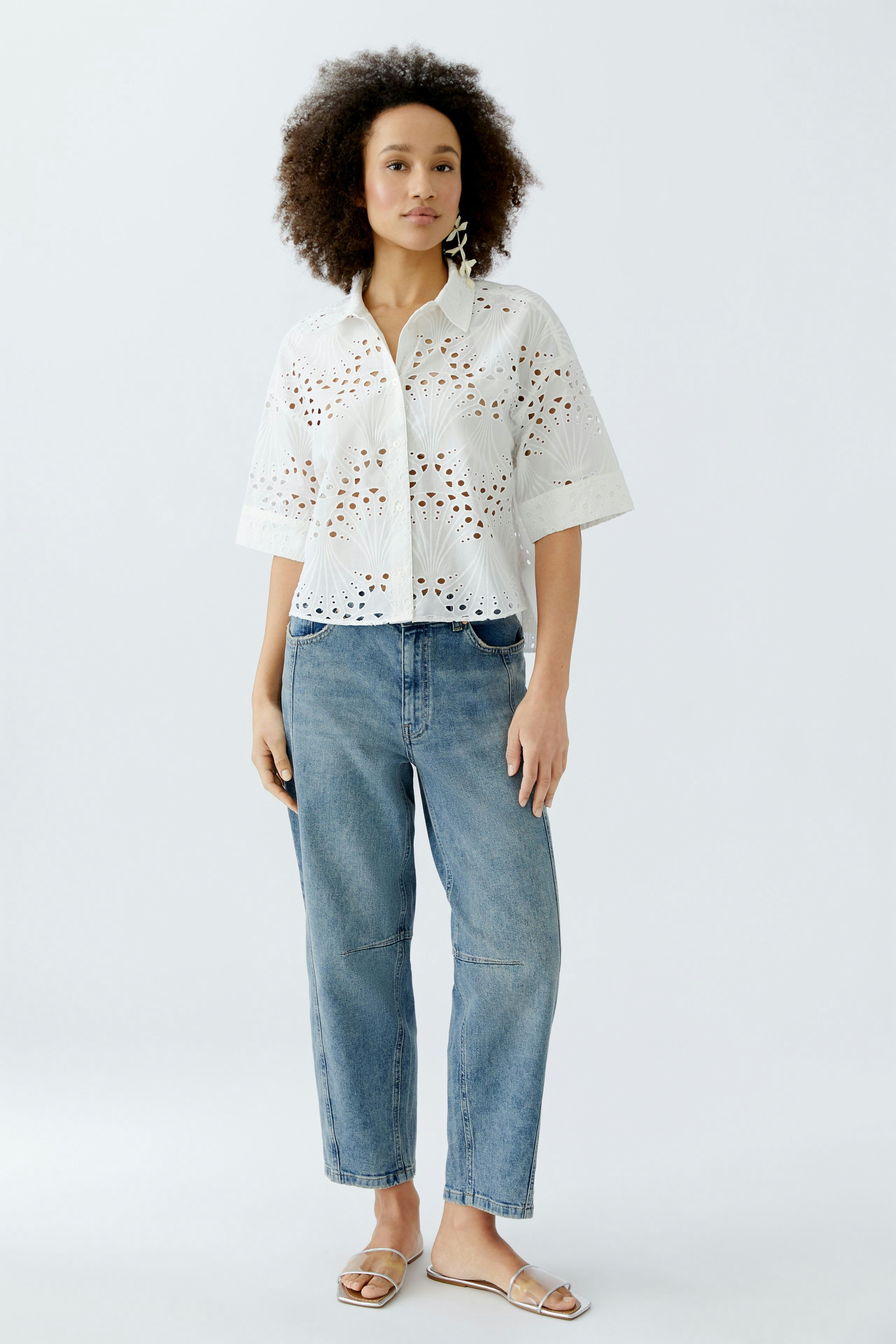 Casual women's blouse: A woman in a white eyelet blouse paired with relaxed jeans.
