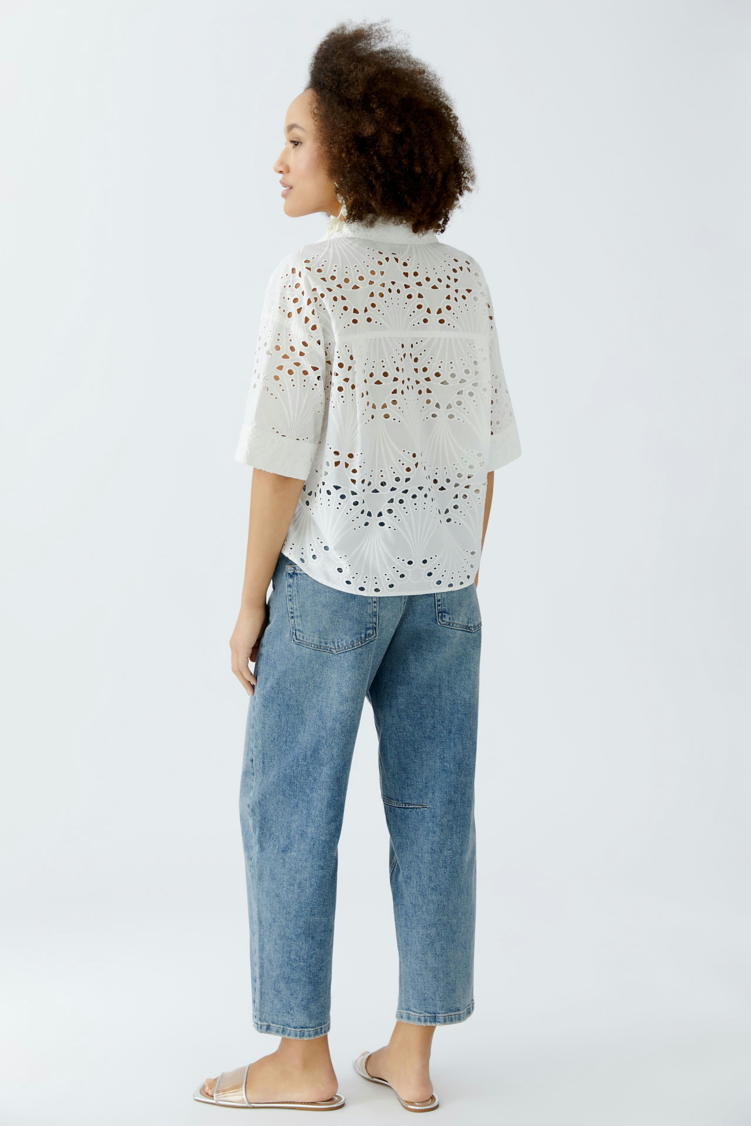Lightweight blouse: Woman in a white, patterned blouse paired with relaxed denim jeans.