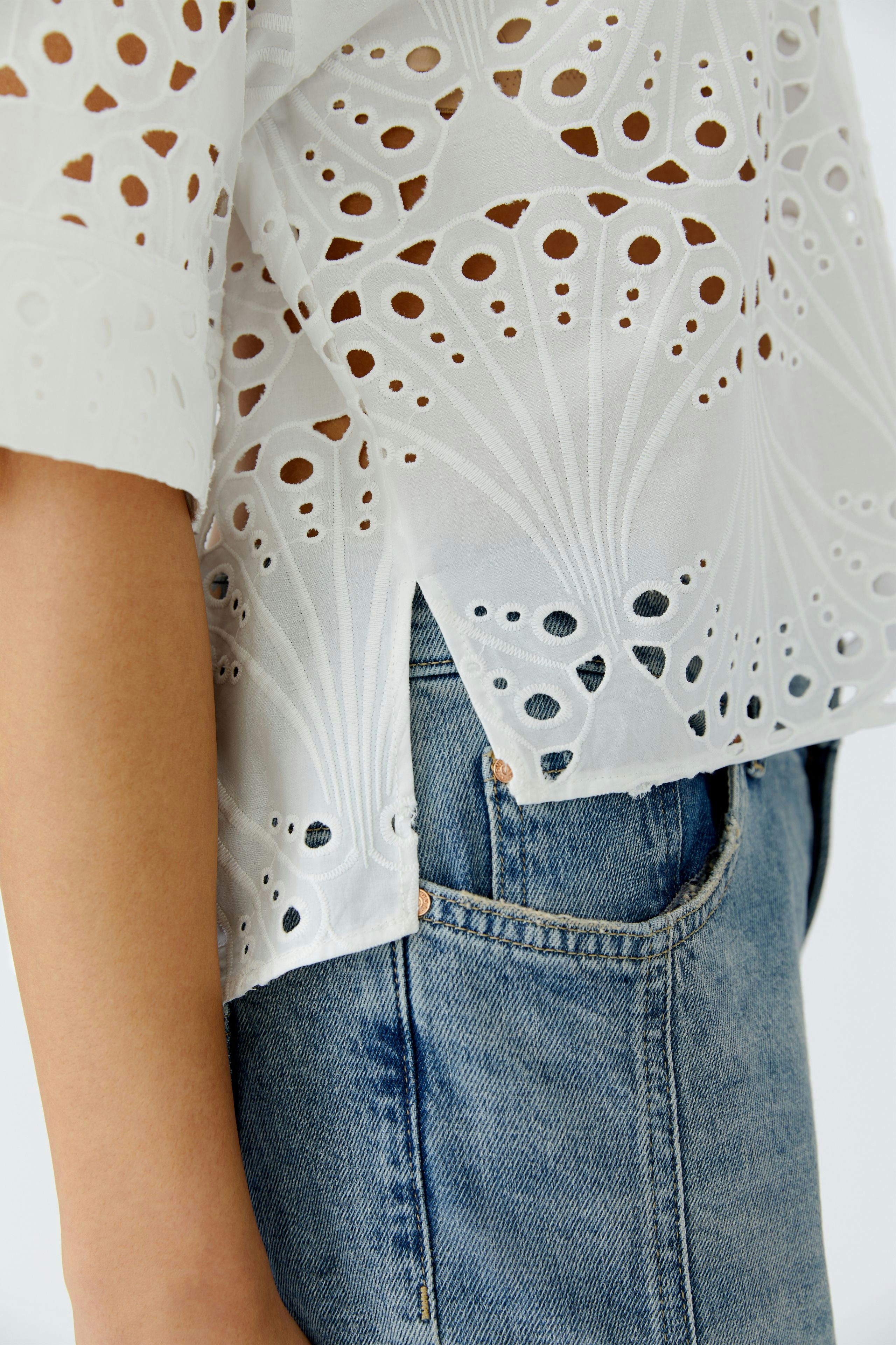Lightweight women's blouse with intricate cut-out details, paired with casual denim.