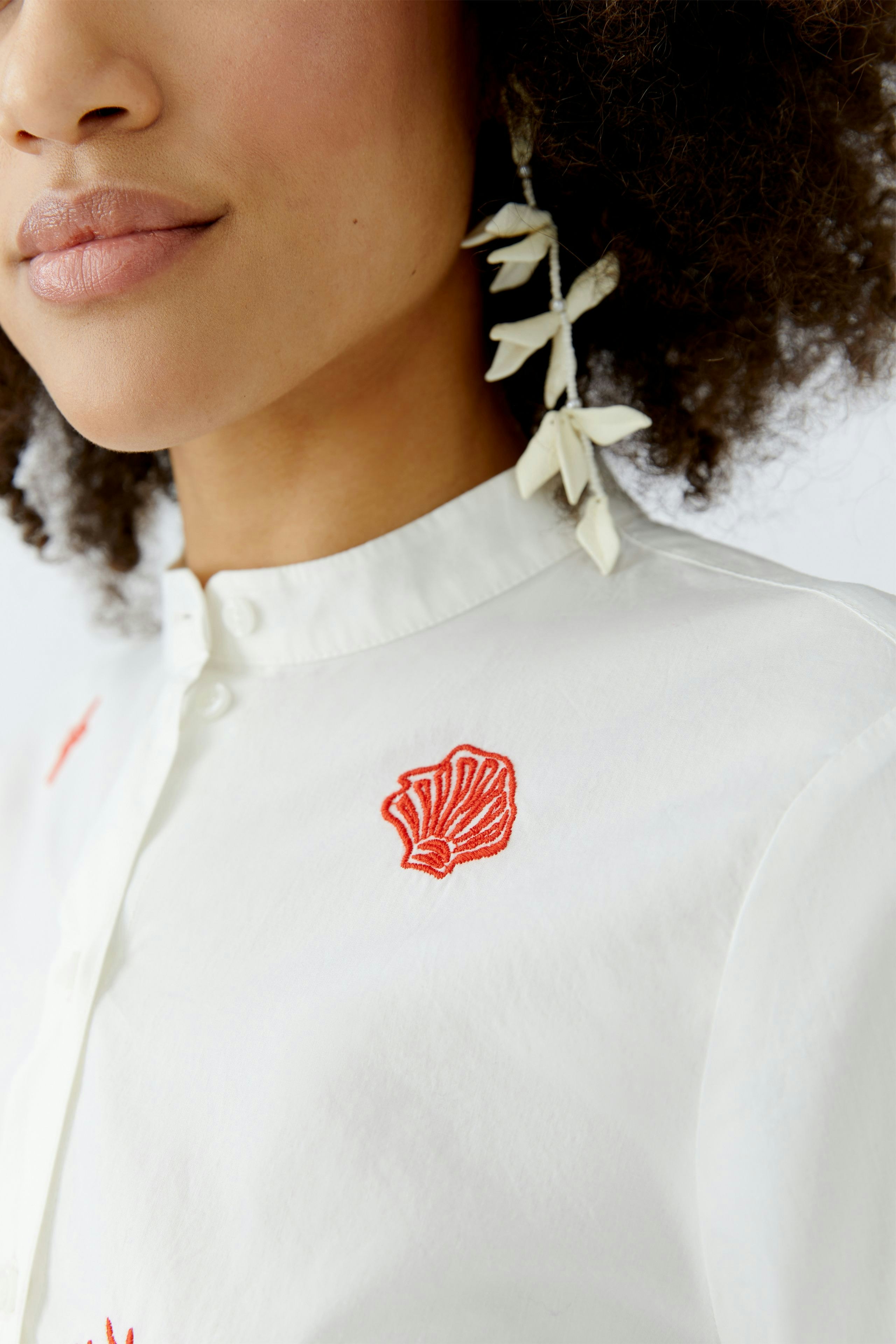 Damen-Bluse: Frau mit weißer Bluse und rotem Muschel-Stickerei, lässiger Look.
