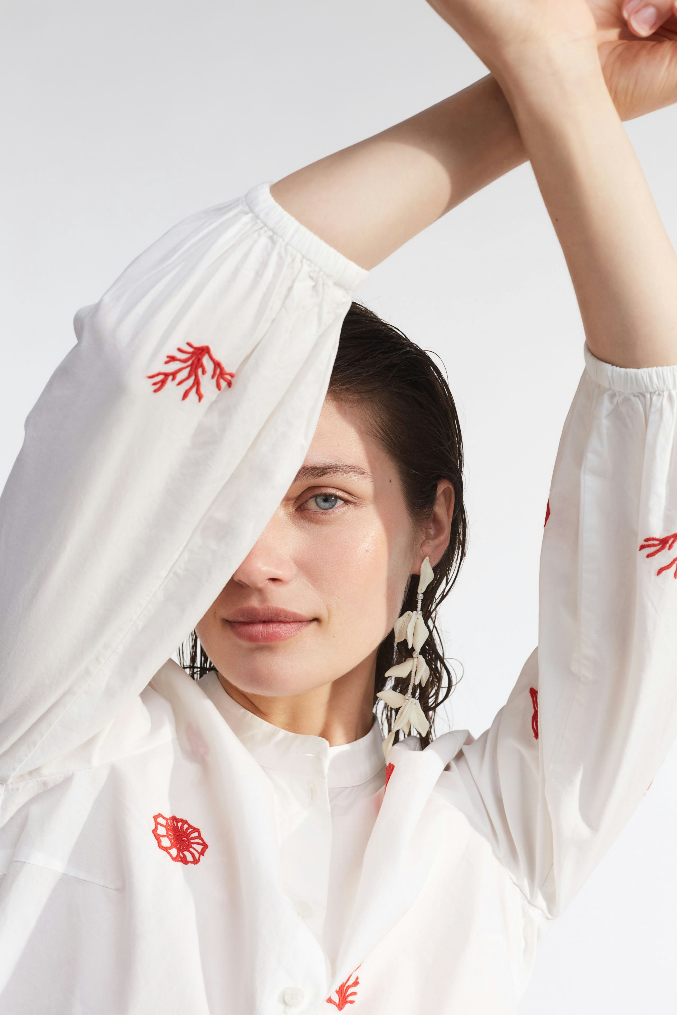 Moderne Damen-Bluse: Frau mit gestickten Details in Weiß und Rot, lässig und frisch.