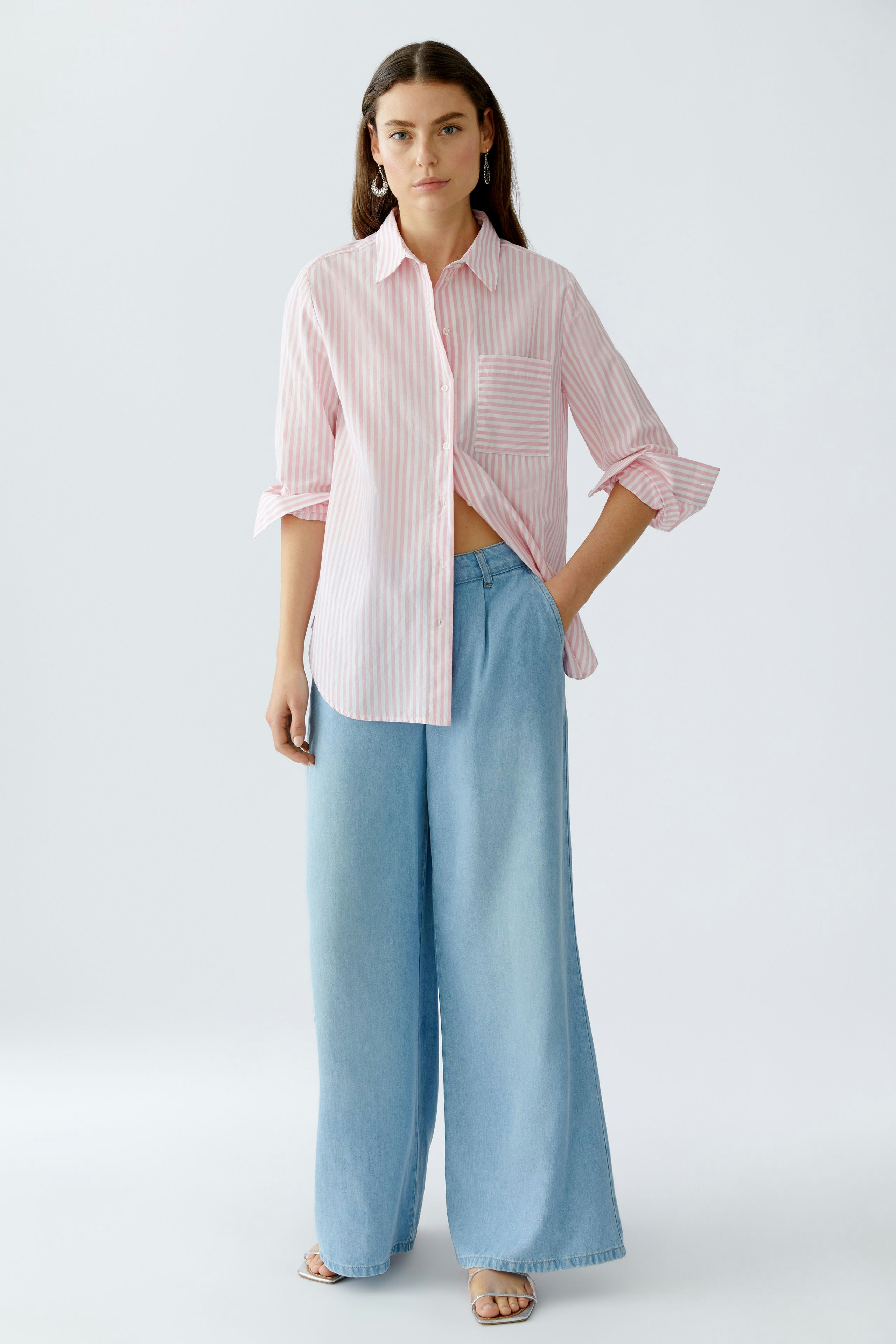 Lässige Hemdbluse: Junge Frau in gestreifter Bluse mit lockerer Passform und weit geschnittenen Jeans.