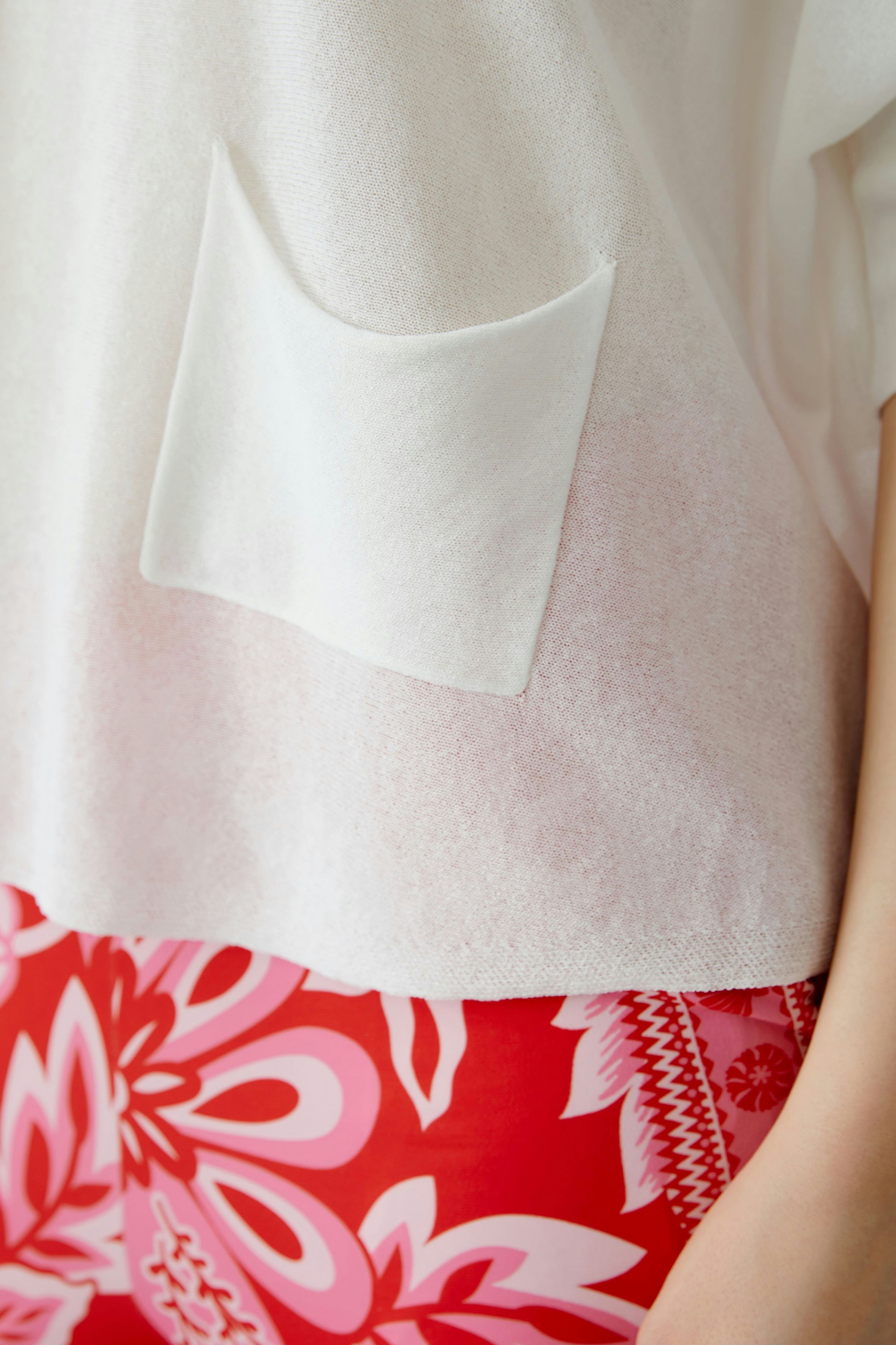 Lässiger Damen-Pullover in Weiß mit praktischer Tasche, kombiniert mit bunten Leggings.