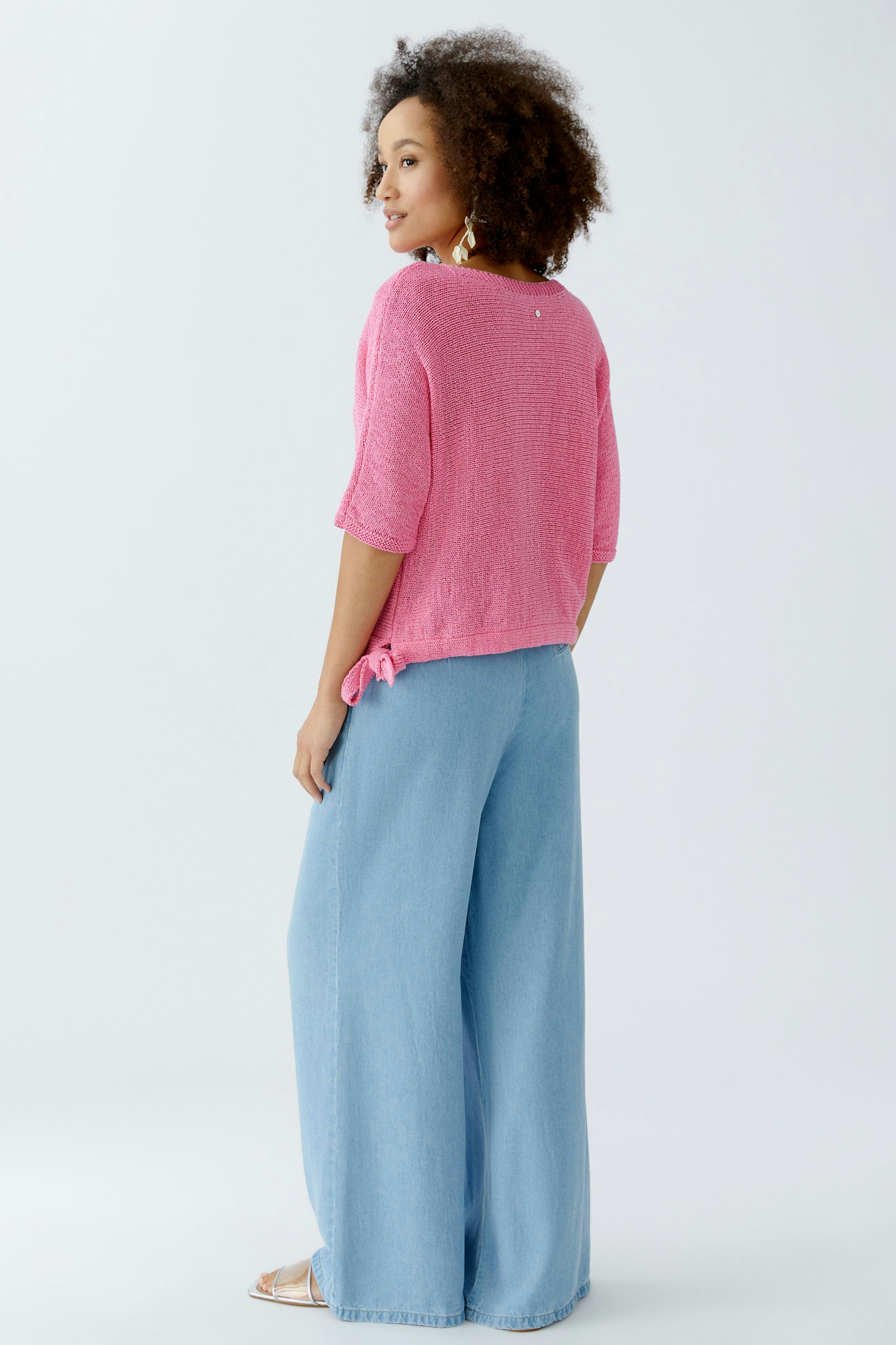 Casual women's pullover: Young woman in a pink pullover with a relaxed fit and stylish wide-leg pants.