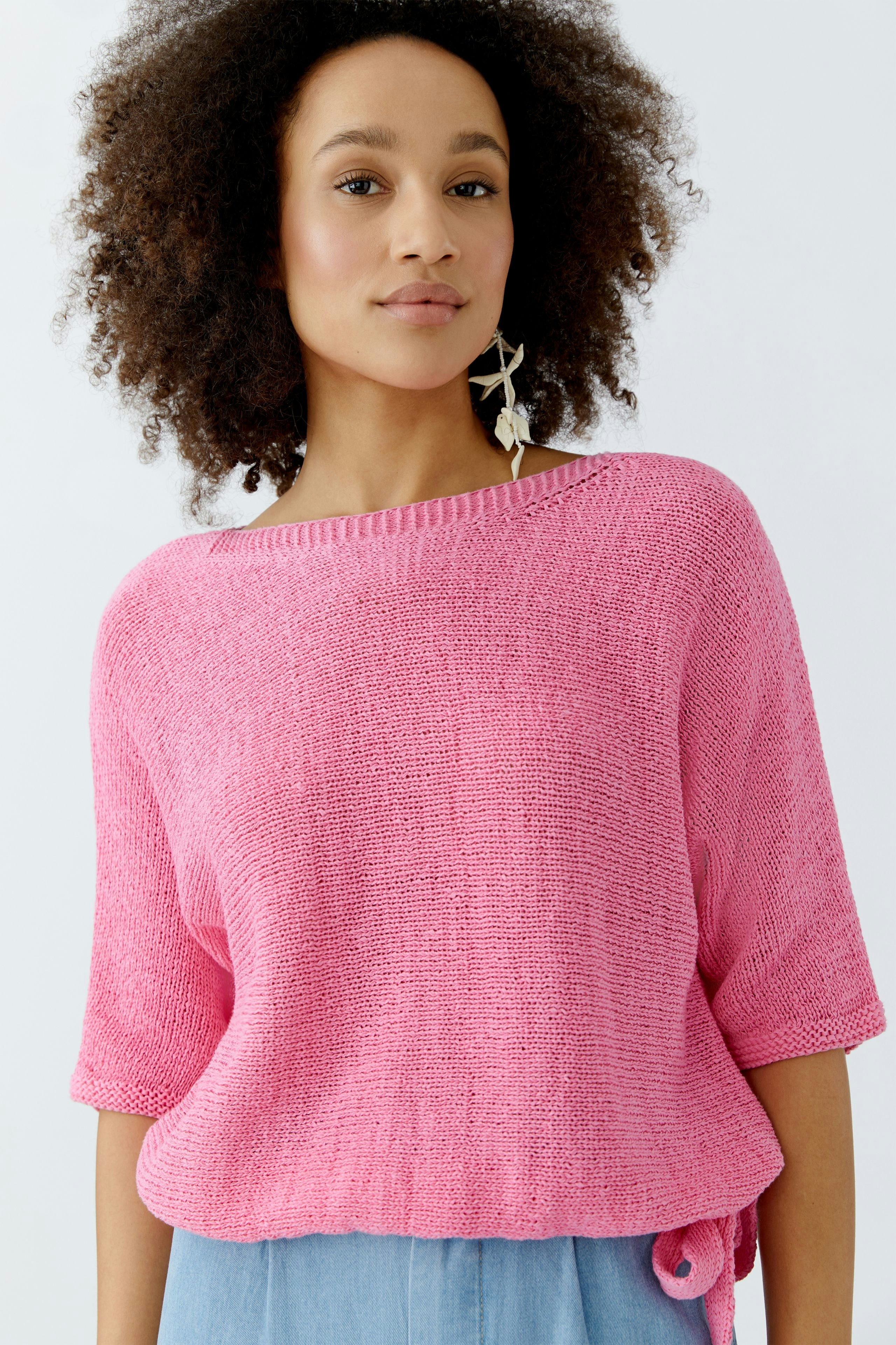 Casual women's pullover: A woman in a pink knitted pullover with a relaxed fit and short sleeves.