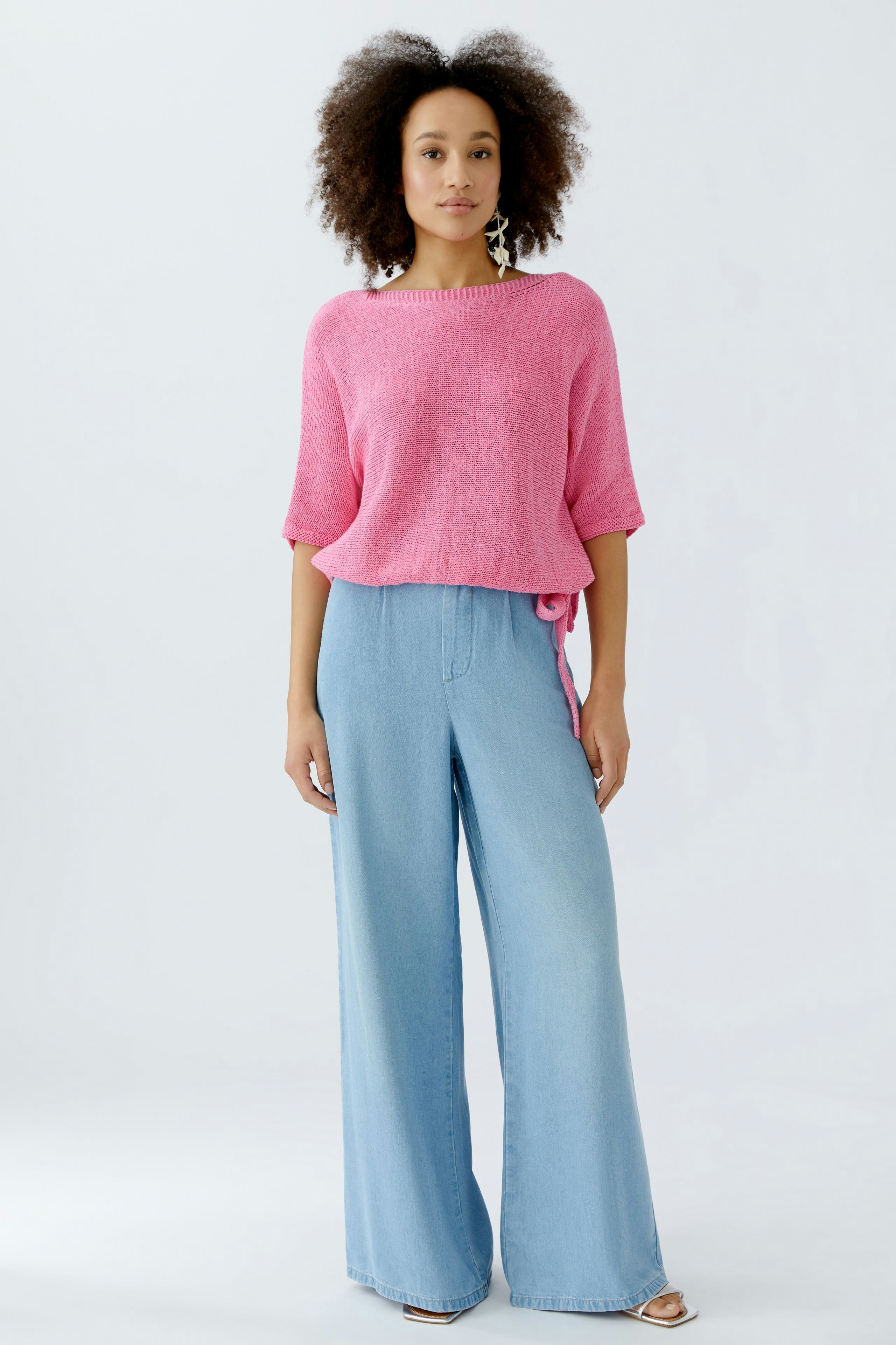 Casual women's pullover: A woman in a pink knit pullover paired with wide-leg jeans.