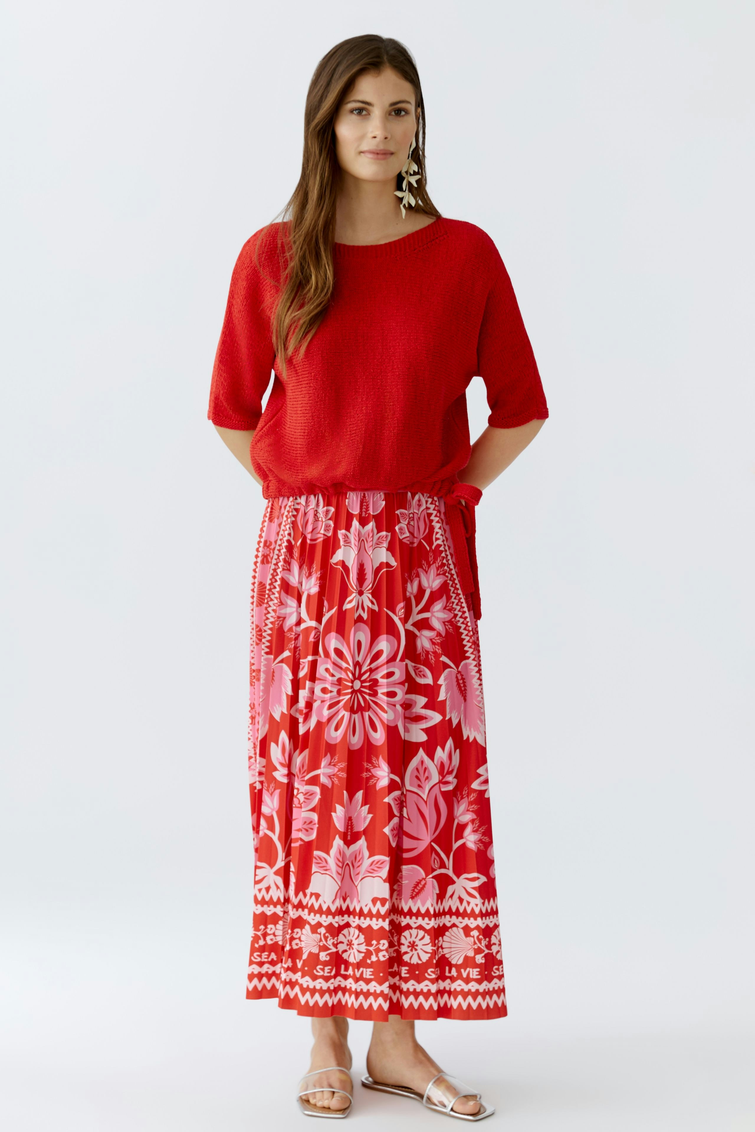 Casual women's pullover: A woman in a red pullover paired with a vibrant floral skirt.