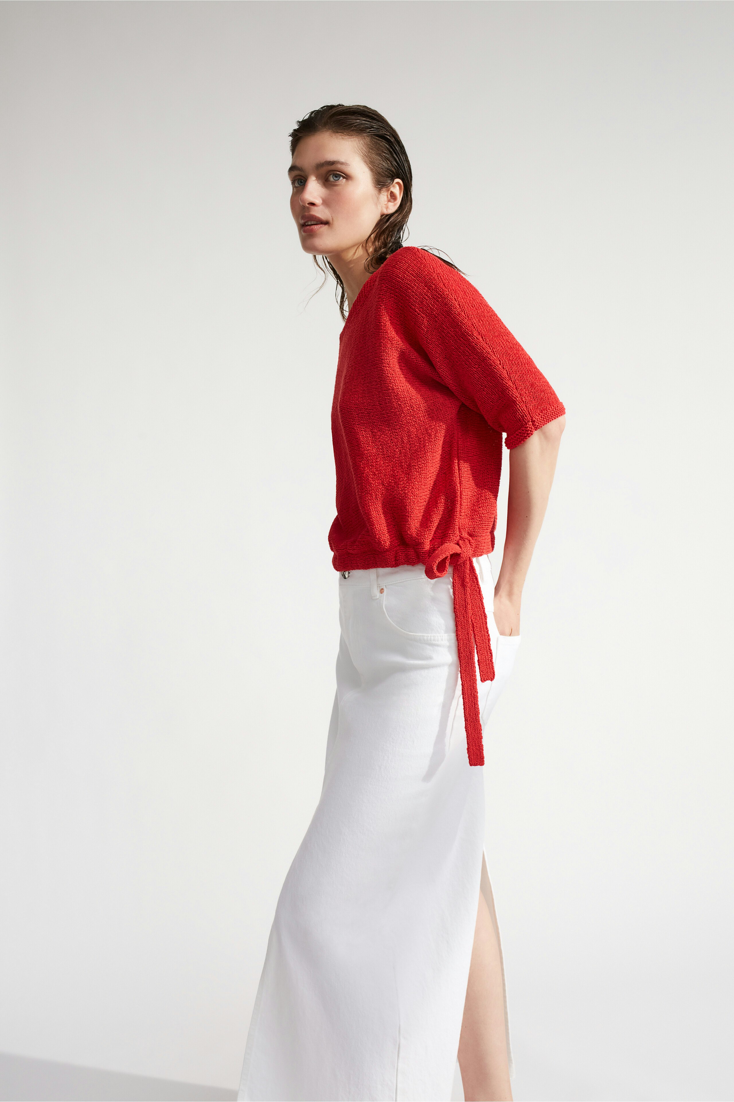 Casual women's pullover: Young woman in a red textured pullover with a relaxed fit.