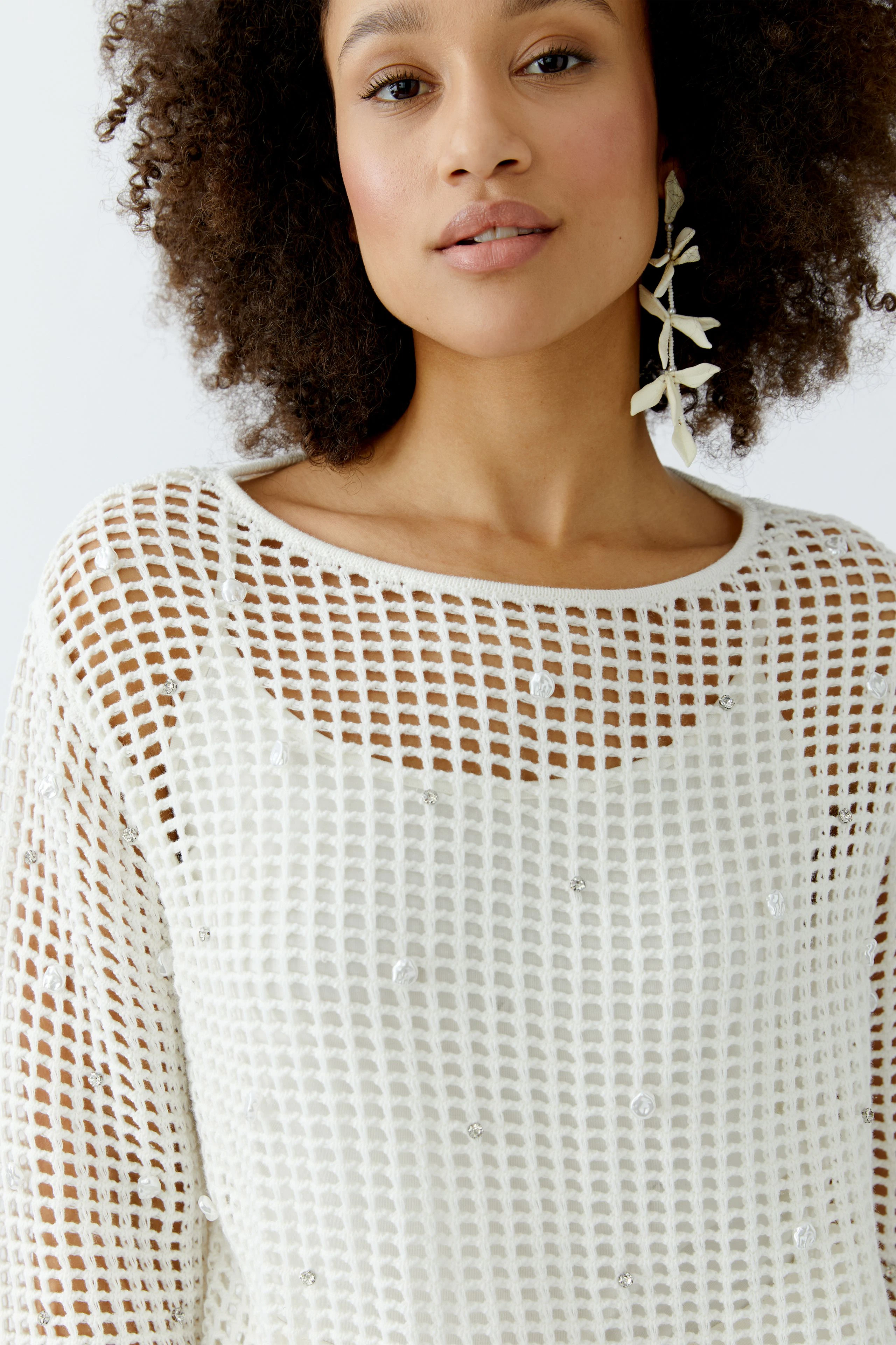 Casual women's pullover: Young woman in a white open-knit pullover with decorative details.