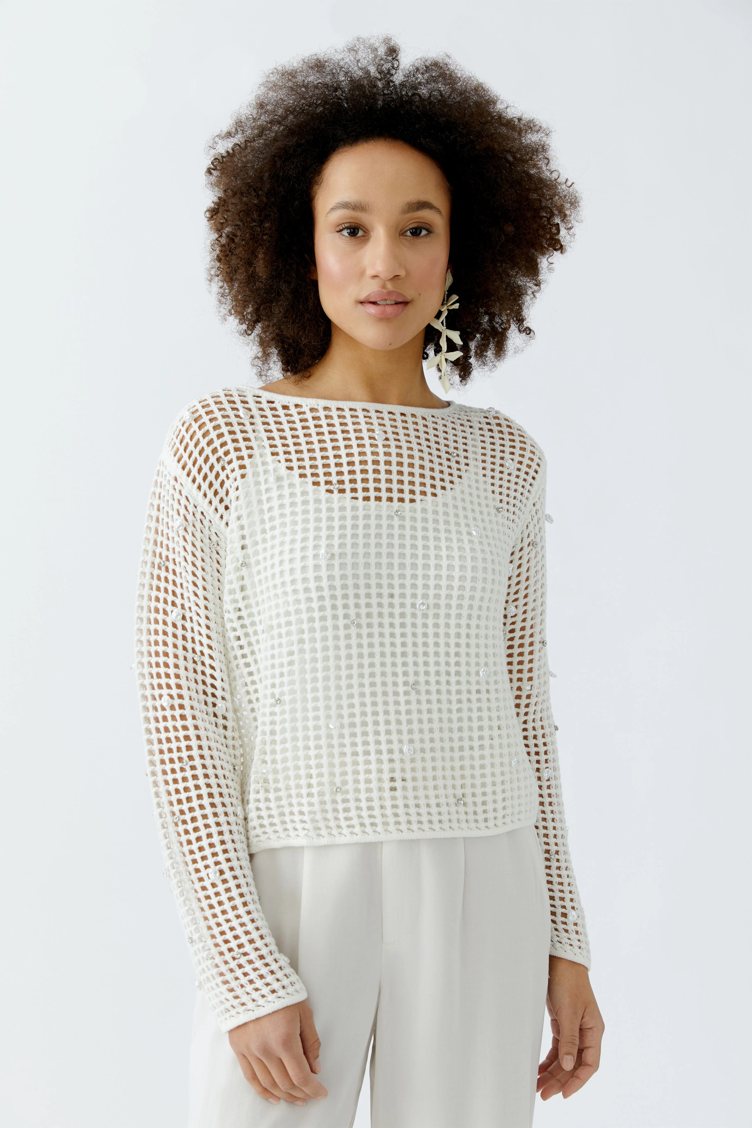 Casual women's pullover: A woman in a white mesh pullover with a relaxed fit and wide neckline.