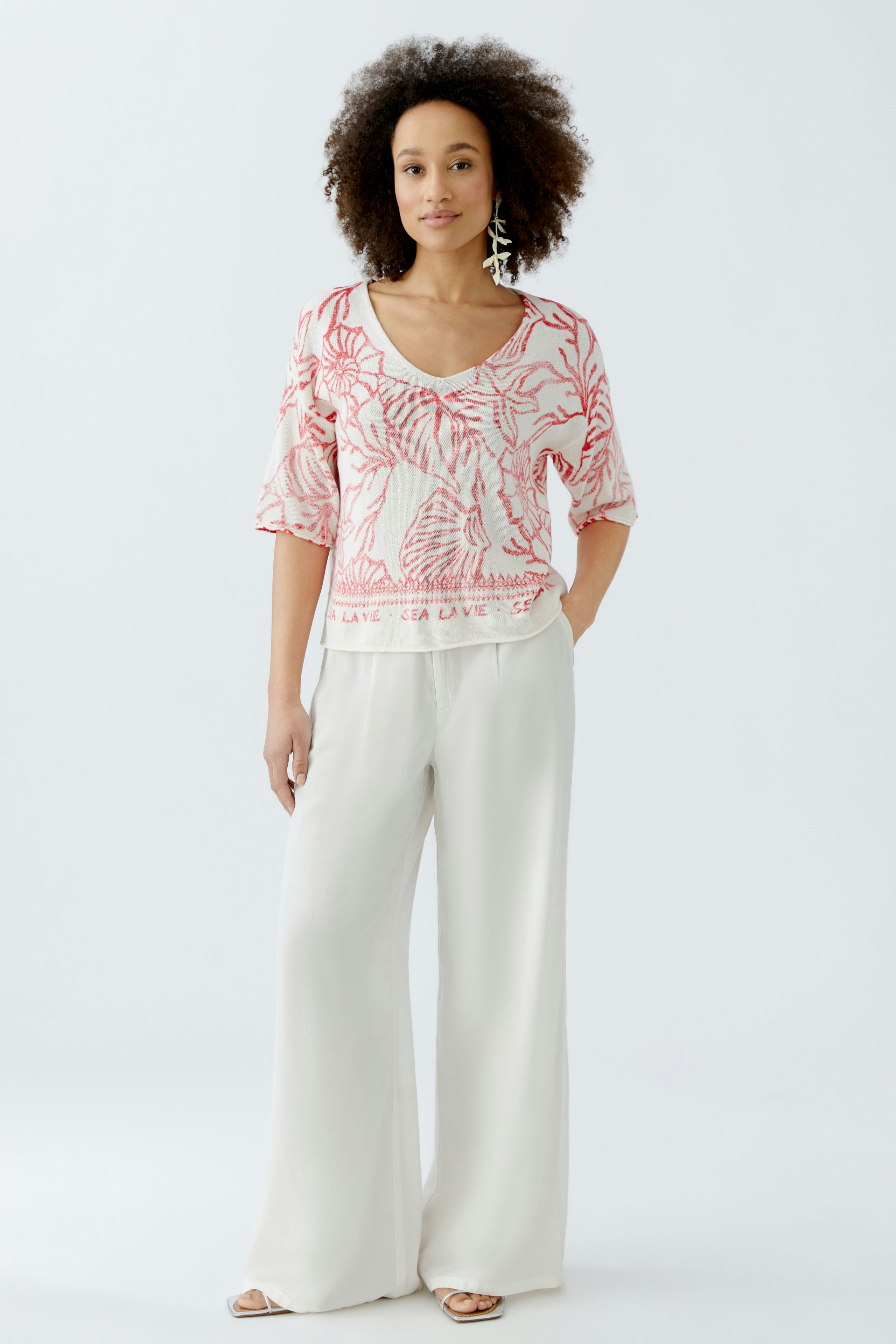 Damen-Pullover: Frau in pinkem, floralem Strickpullover mit weitem Schnitt und lässigen Hosen.