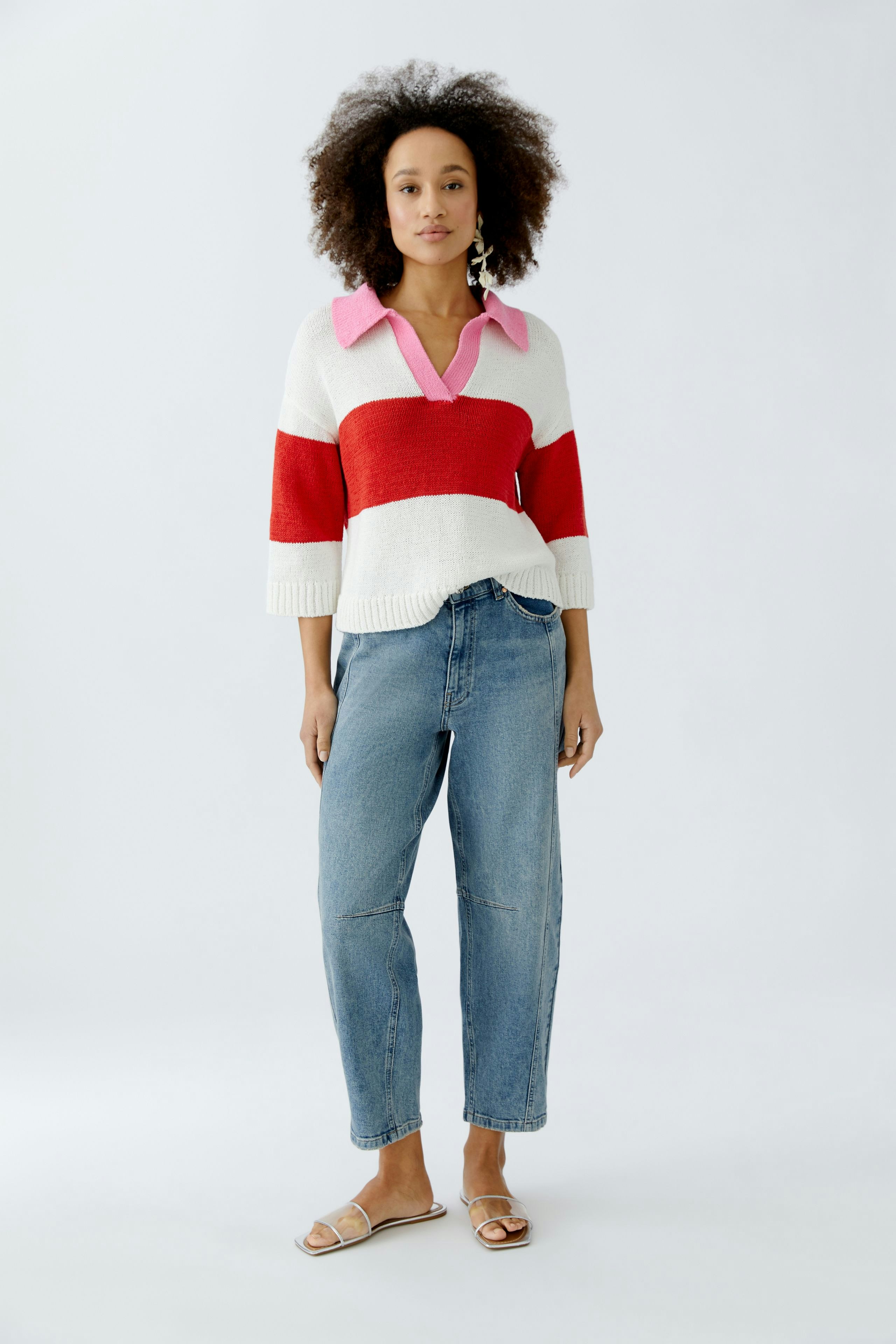 Casual women's pullover: Young woman in a striped pullover with a pink collar and relaxed jeans.
