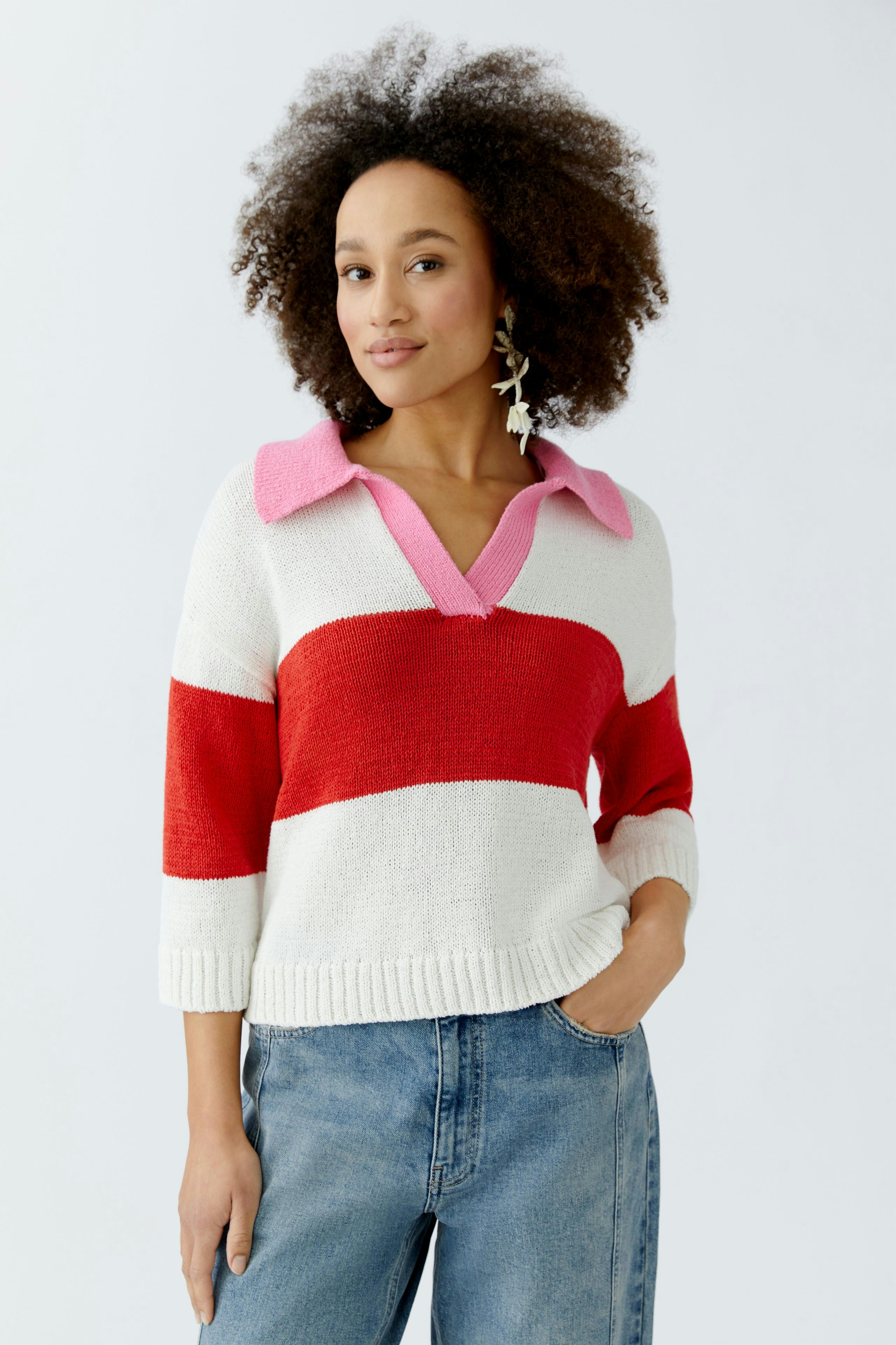 Casual women's pullover: A woman in a striped pullover with red and pink accents, paired with jeans.