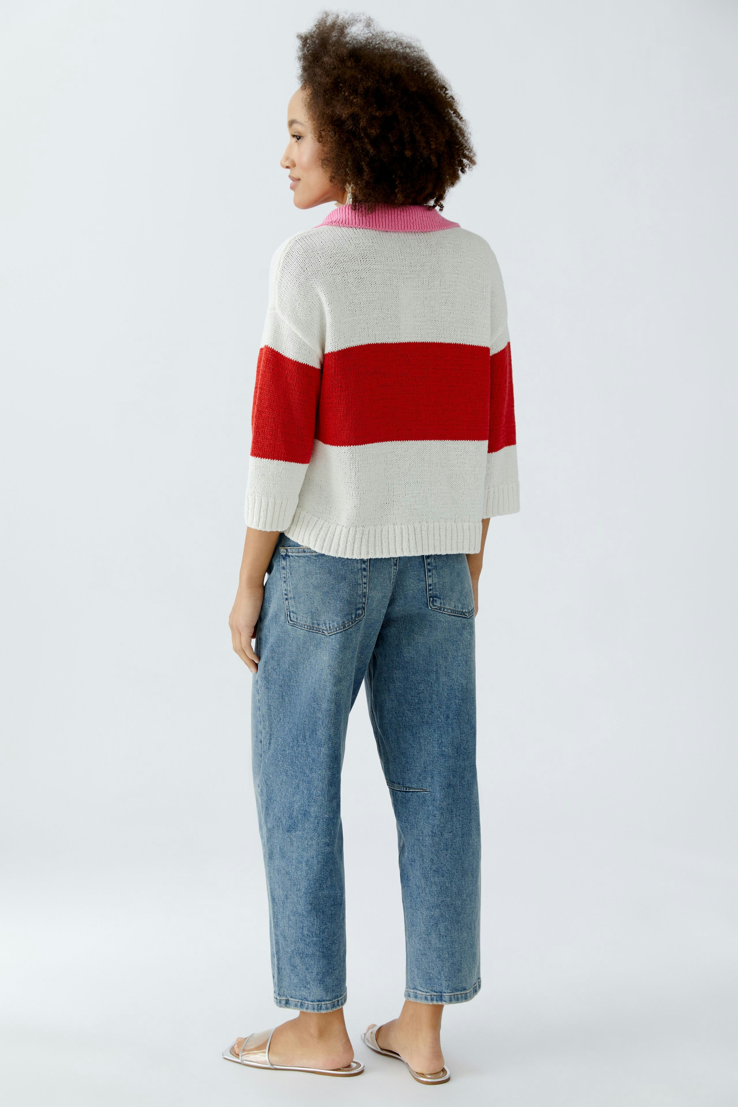 Casual women's pullover: A woman in a striped pullover with red and white colors, paired with relaxed jeans.