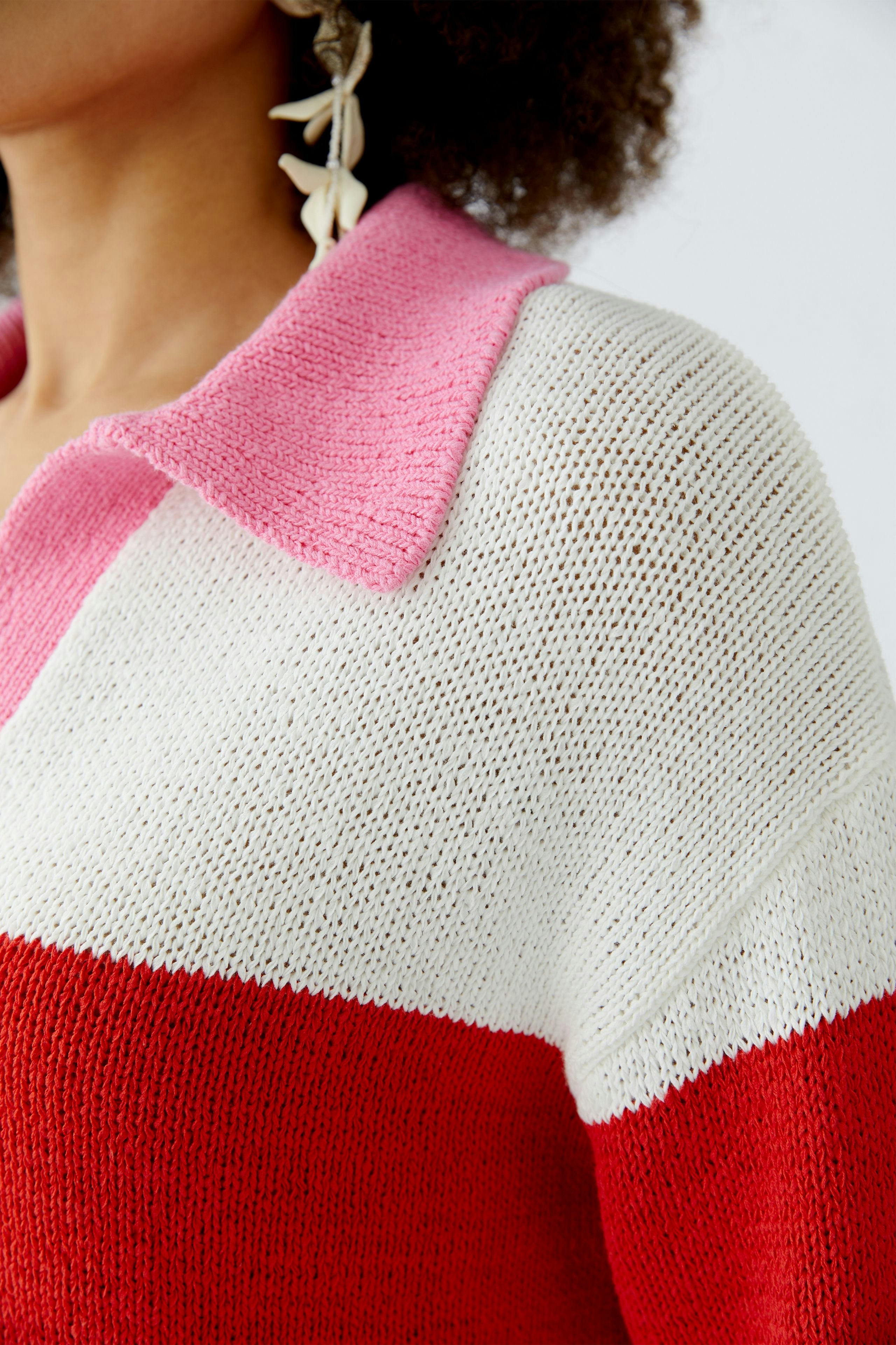 Casual women's pullover: Close-up of a colorful knit pullover with a pink collar and bold stripes.