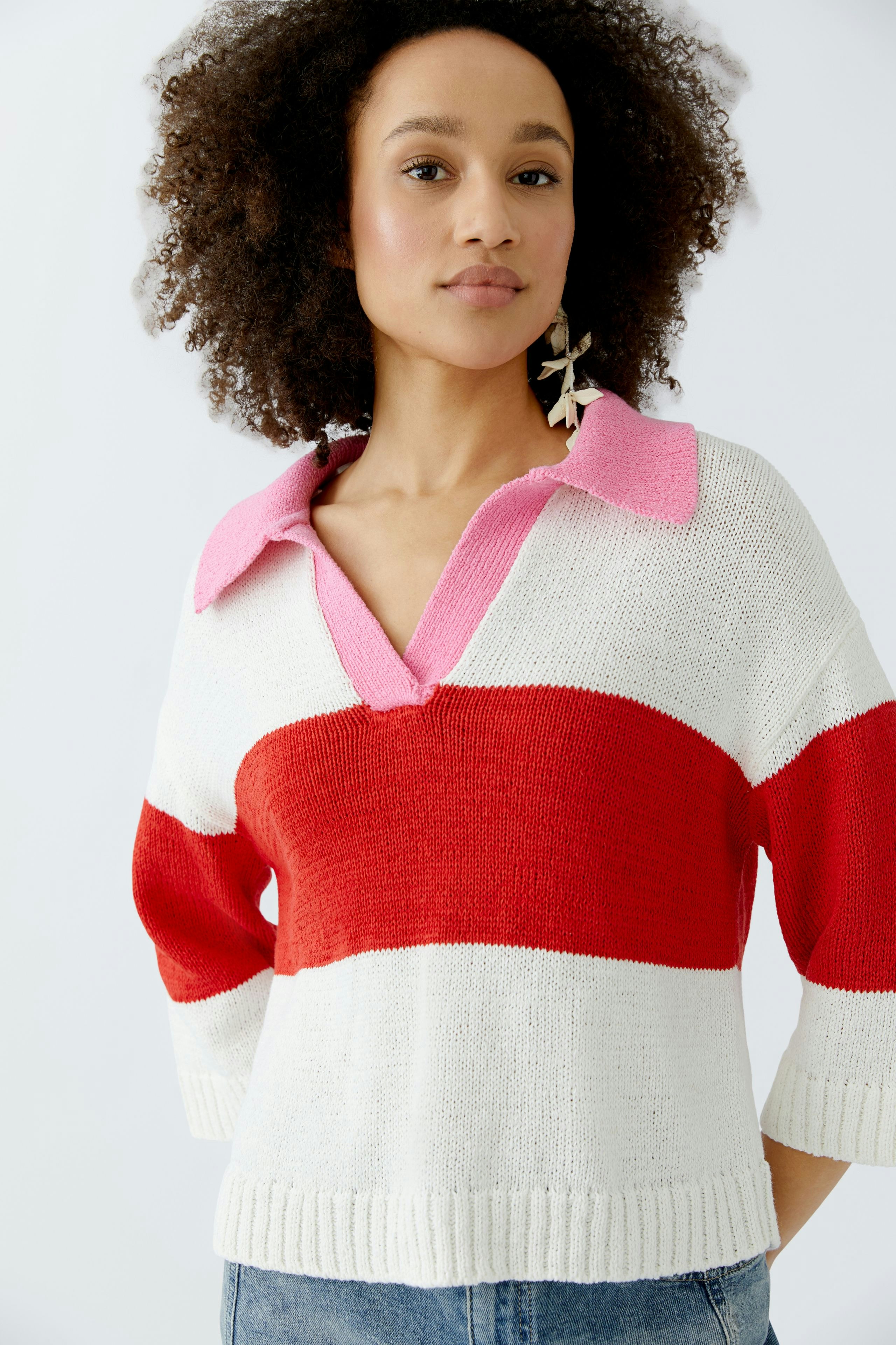 Casual women's pullover: A woman in a striped pullover with red and pink accents poses confidently.