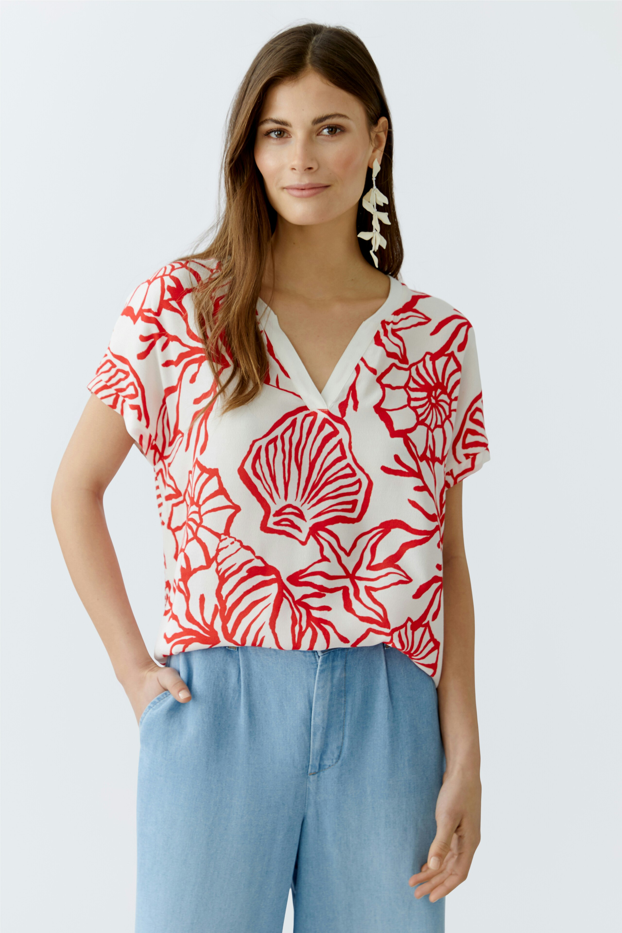 Casual women's blouse shirt: Woman in a short-sleeved top with a vibrant floral pattern and relaxed fit.